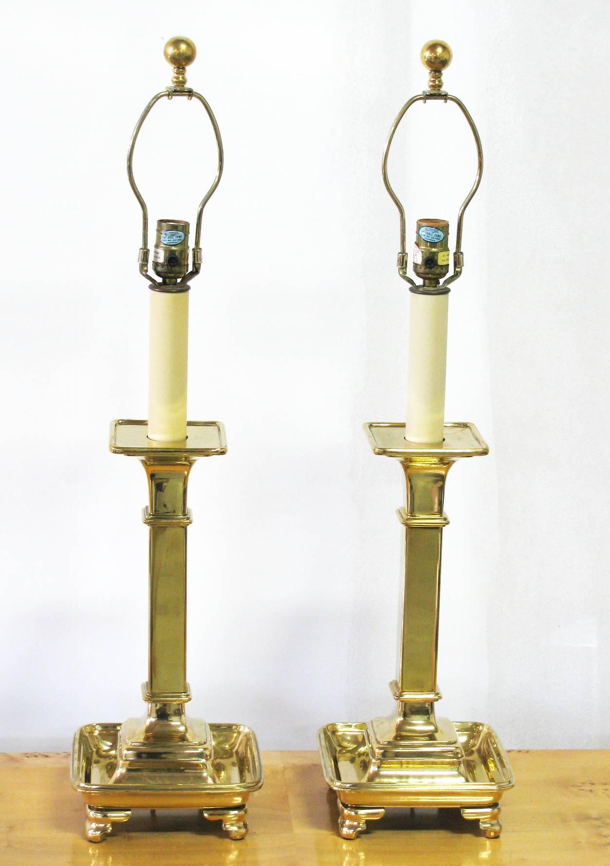 A classical style pair of quality table lamps of solid brass by Chapman. The lamps are substantial and heavy, polished brass and feature a single (three-way) socket and brass ball finial. Shades are not included.