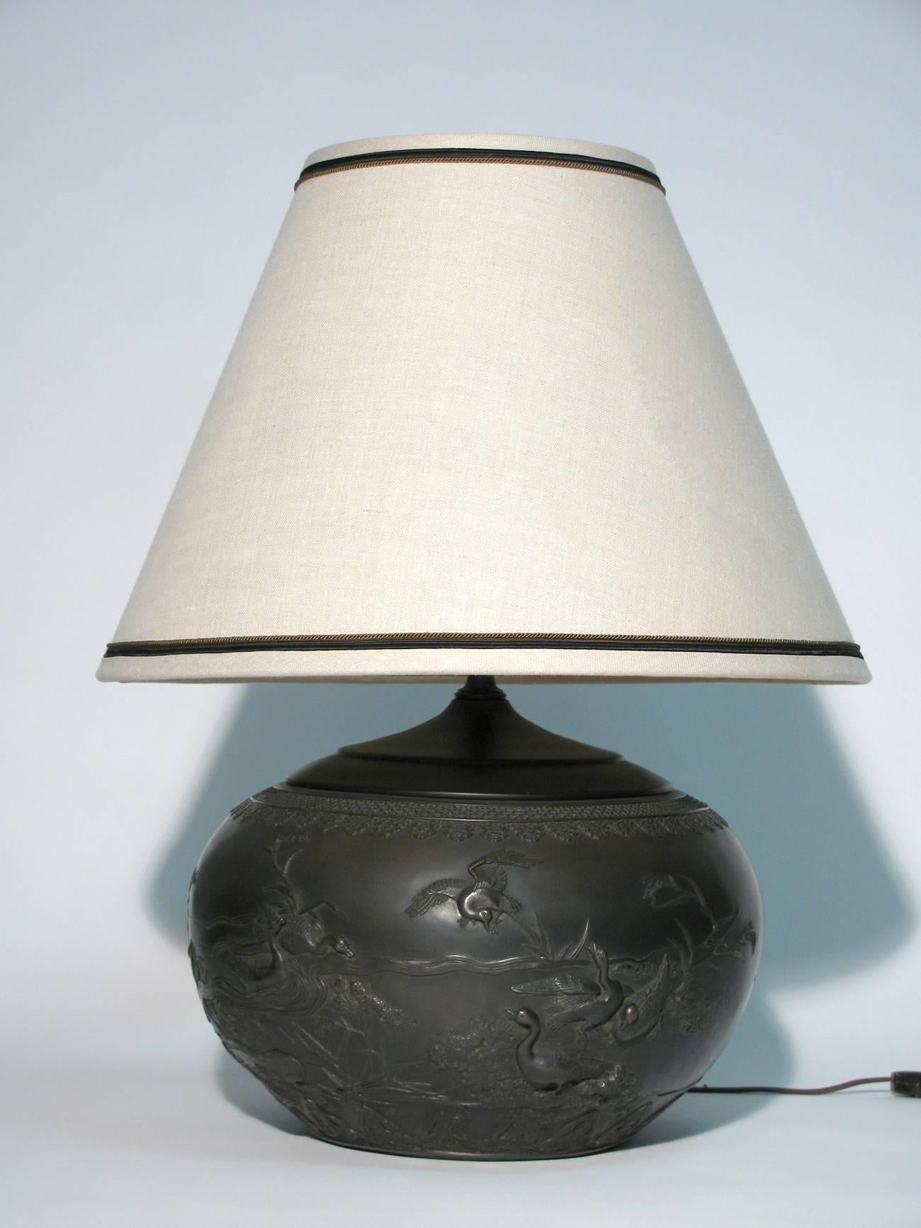 A stunning pair of heavy table lamps in the chinoiserie taste. The lamps are a rich brown ceramic and have the look of dark patina bronze, boubous in form and have blackened metal caps on top. Single socket with three-way switch. Measures: Height