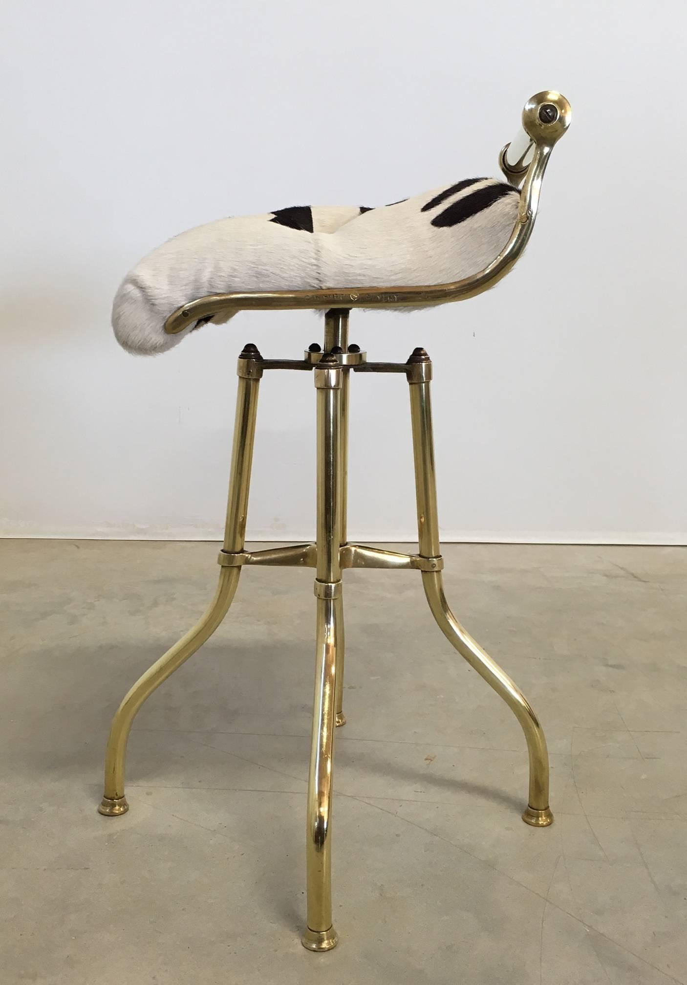 English brass revolving stool with tufted zebra print hair-on-hide seat, circa 1890. The seat swivels in all directions and the height is adjustable 24 to 28 inches. Stamped on frame, C.H. Hare, patent.