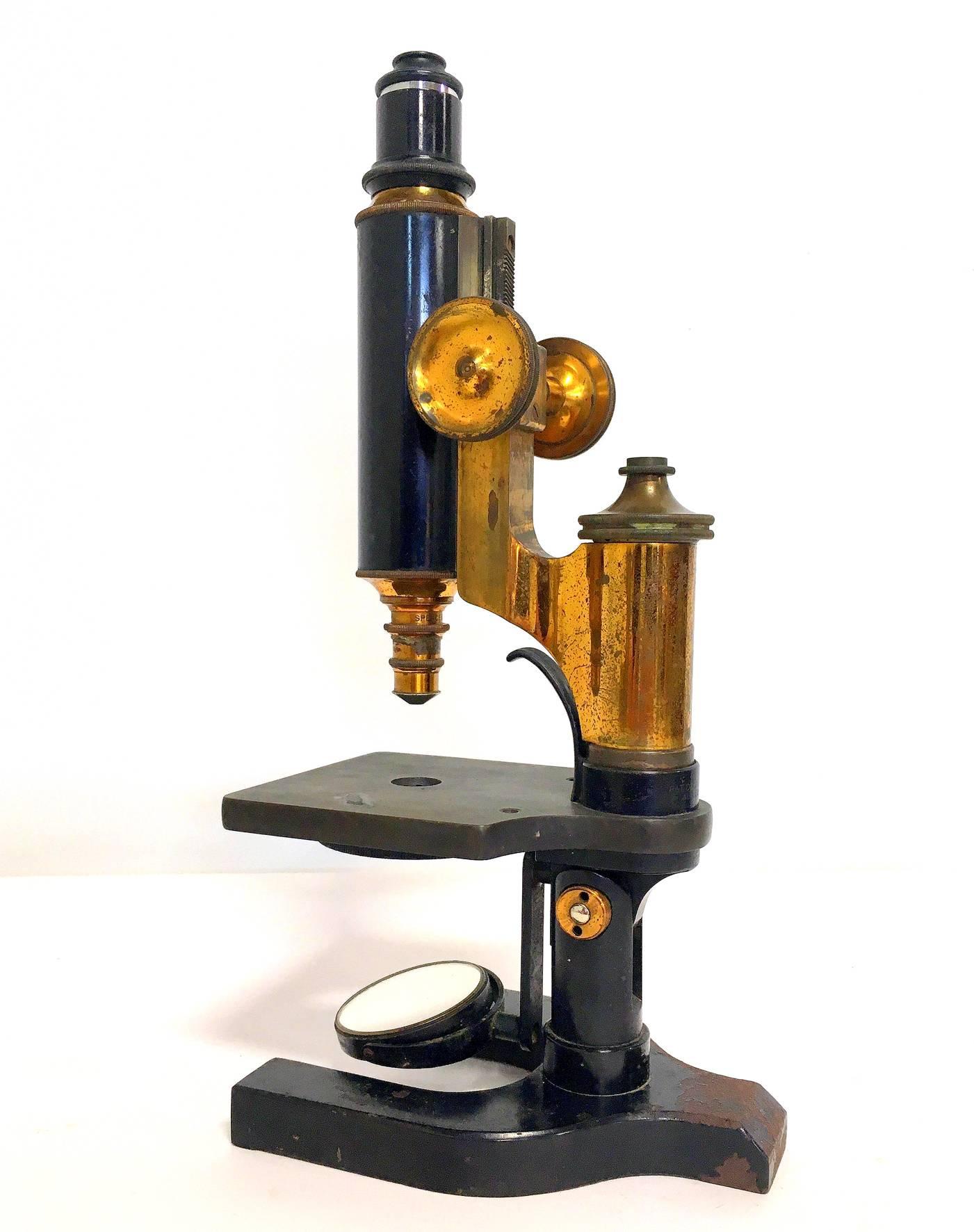 A brass and iron microscope by Spencer of buffalo, New York. circa late 19th century. This microscope is in very good working condition, the brass dials on each side easily glide the sight piece and the round mirror swivels in several directions.