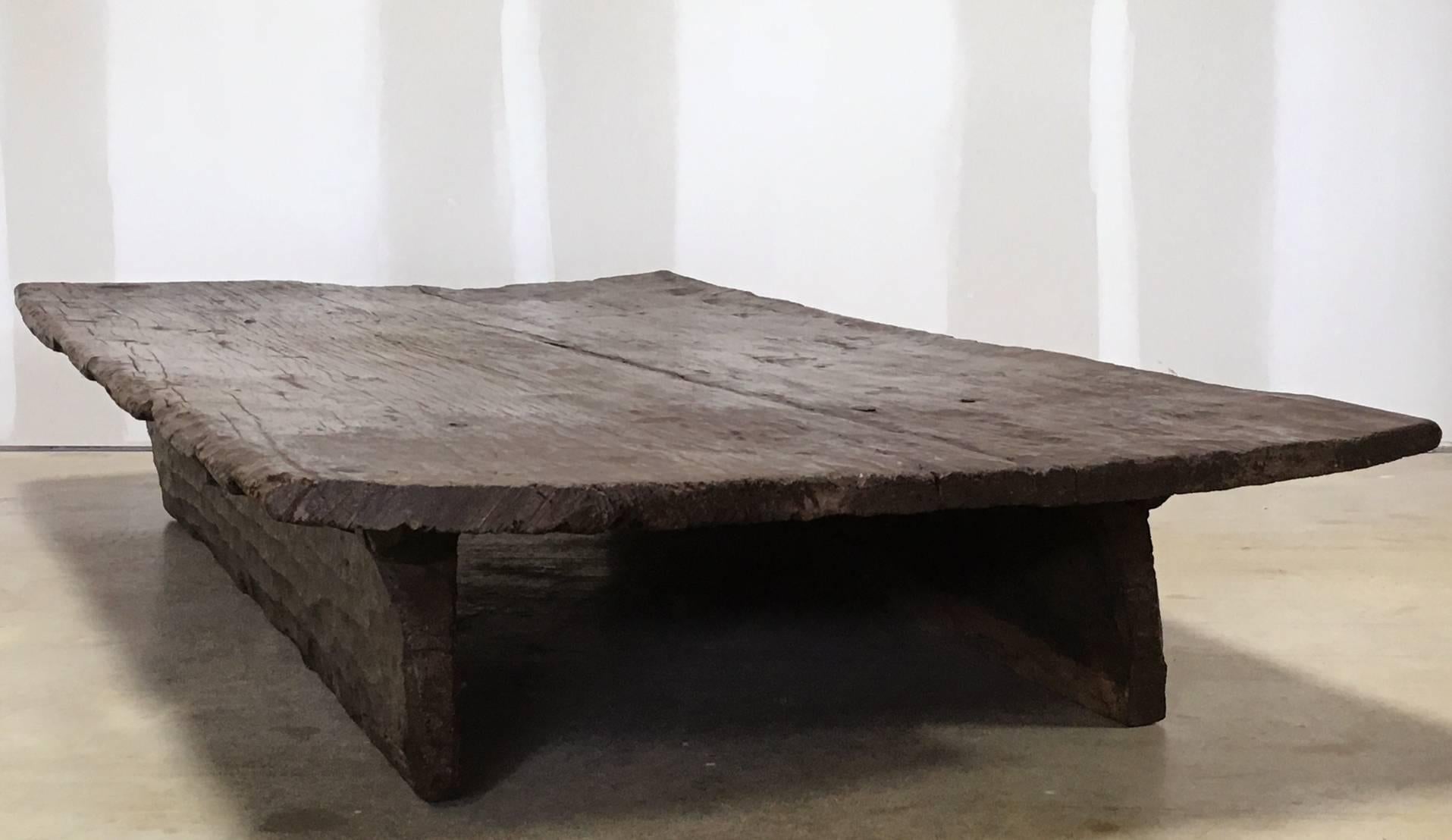 A massive teak single board table, possibly from a temple, circa early 20th century, India. The top is cut from a single piece of wood, and the base is open, with two cut pieces of wood on the sides, and ends being open. A rich and warm patina
