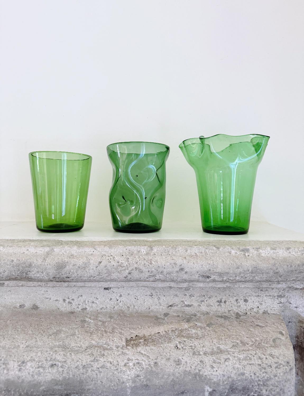 Un ensemble de trois magnifiques vases en verre vert d'Empoli soufflé à la main. Chaque pièce présente de minuscules bulles d'air qui témoignent de sa nature soufflée à la main, ainsi que la marque sur la base où elle a été coupée à partir du tuyau