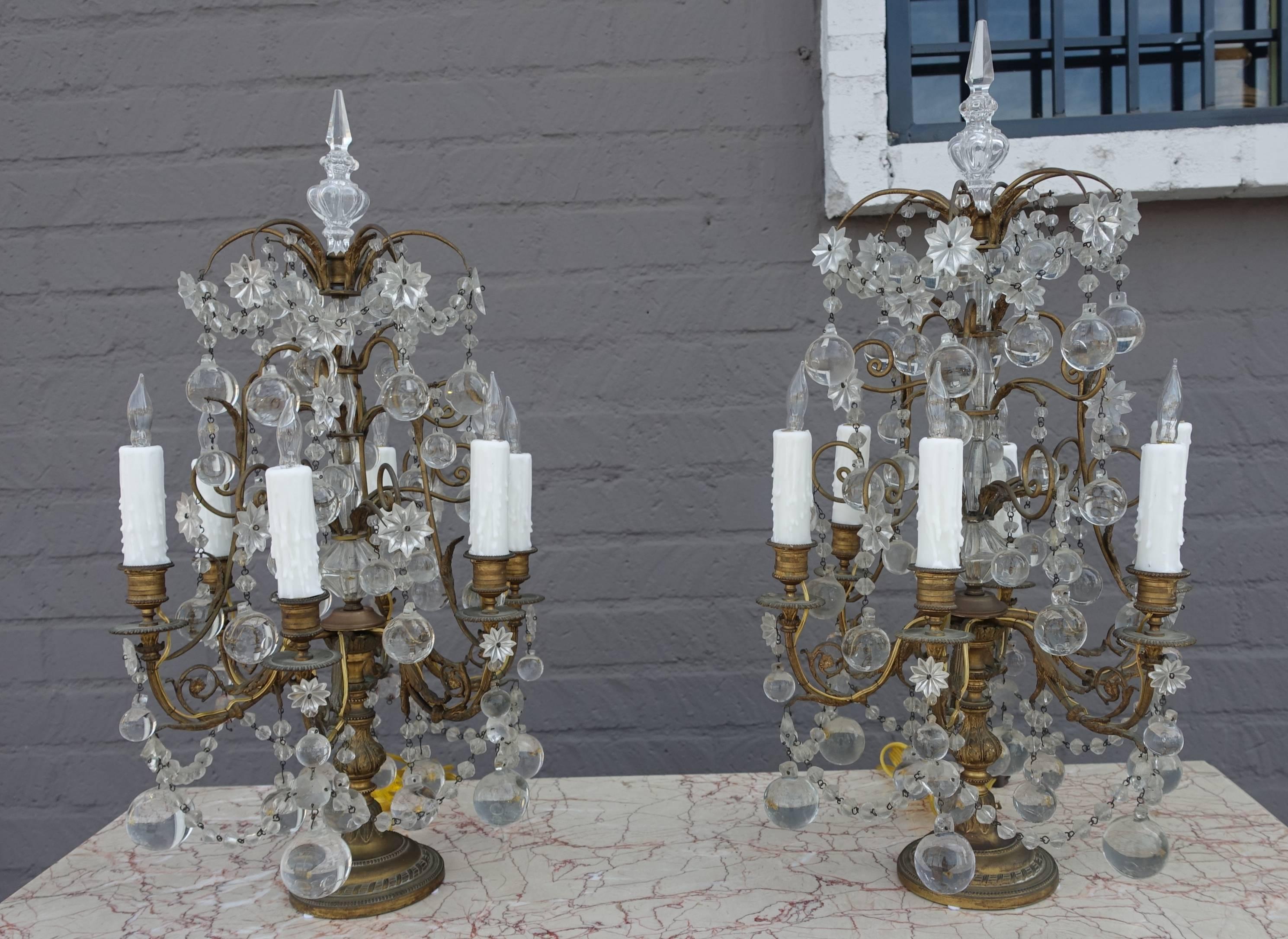 Pair of French six-light bronze and crystal girandoles adorned with garlands of beads, crystal stars and ball drops throughout. The lights have been newly rewired with drip wax candle covers.