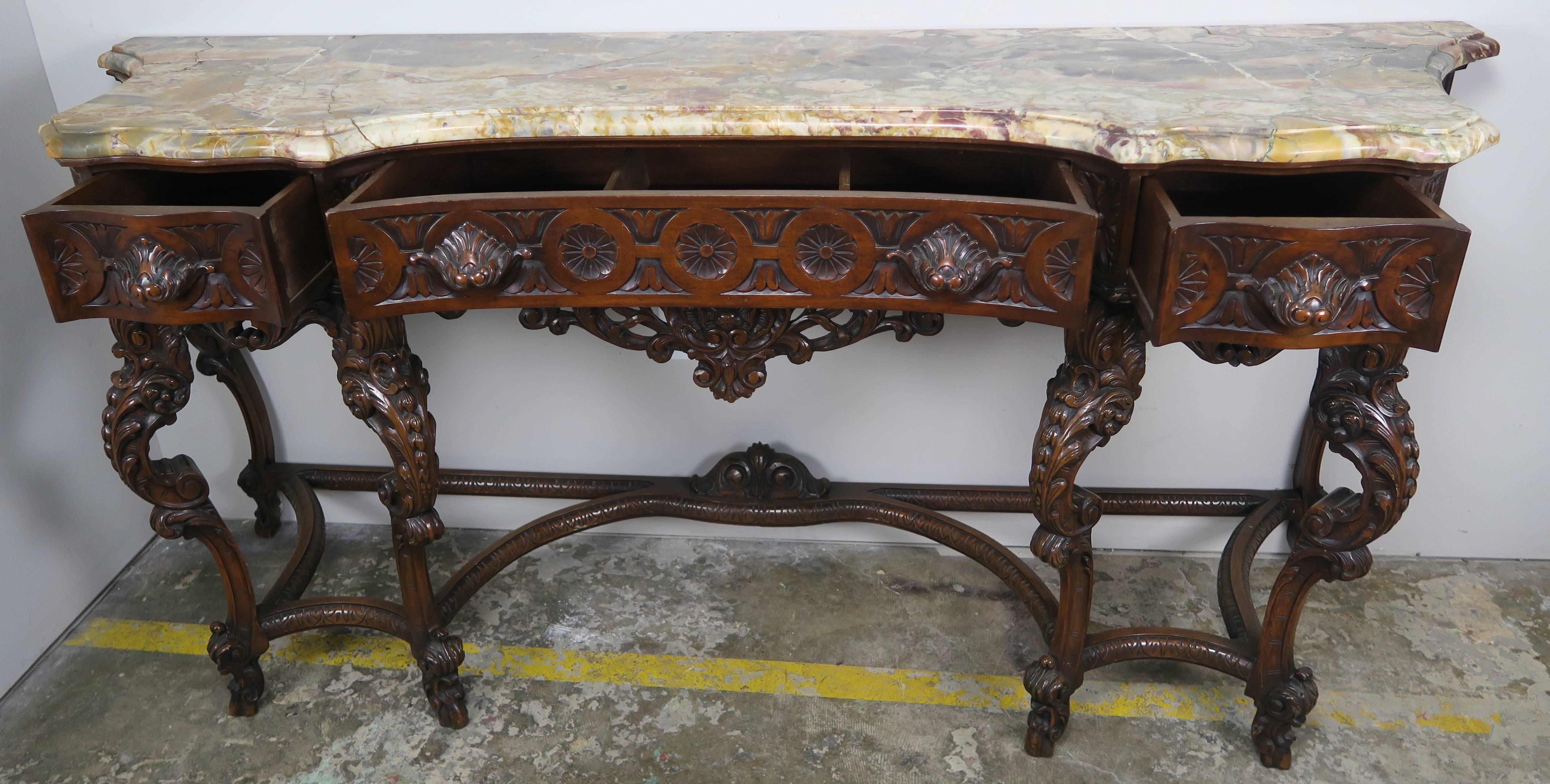 19th century French carved walnut sideboard standing on six cabriole legs. Three drawers with great storage for silver and serving pieces. Detailed carving throughout including carved shell drawer pulls. This shell motif is repeated throughout. Rare