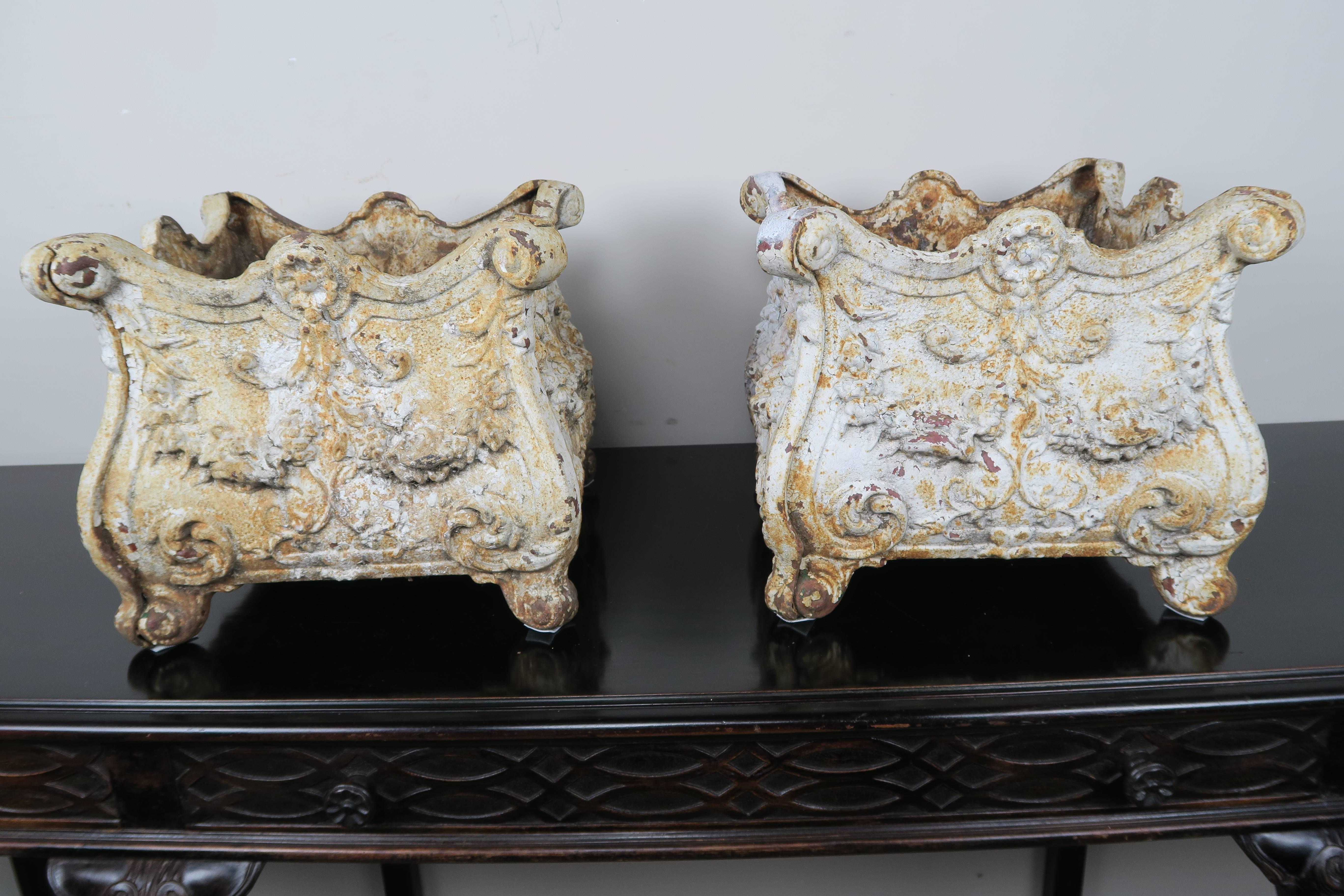 A pair of 19th century French painted cast iron square shaped planters. The planters have beautiful details depicting garlands of flowers. Wonderful worn/weathered finish.