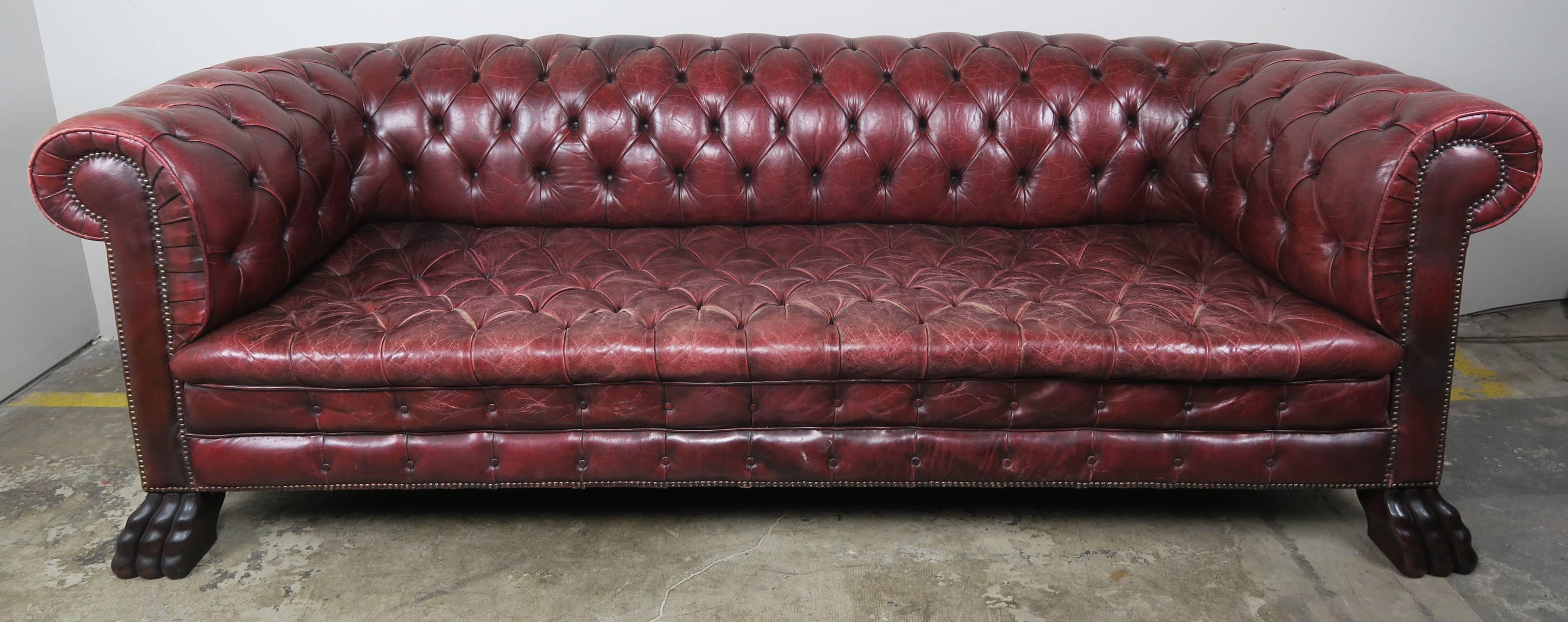 English leather tufted Chesterfield style sofa with hand-carved wood lion's feet and nailhead trim detail. The leather is all original to the Classic style sofa that was made in the early 1900s and still has the original horsehair upholstery. The
