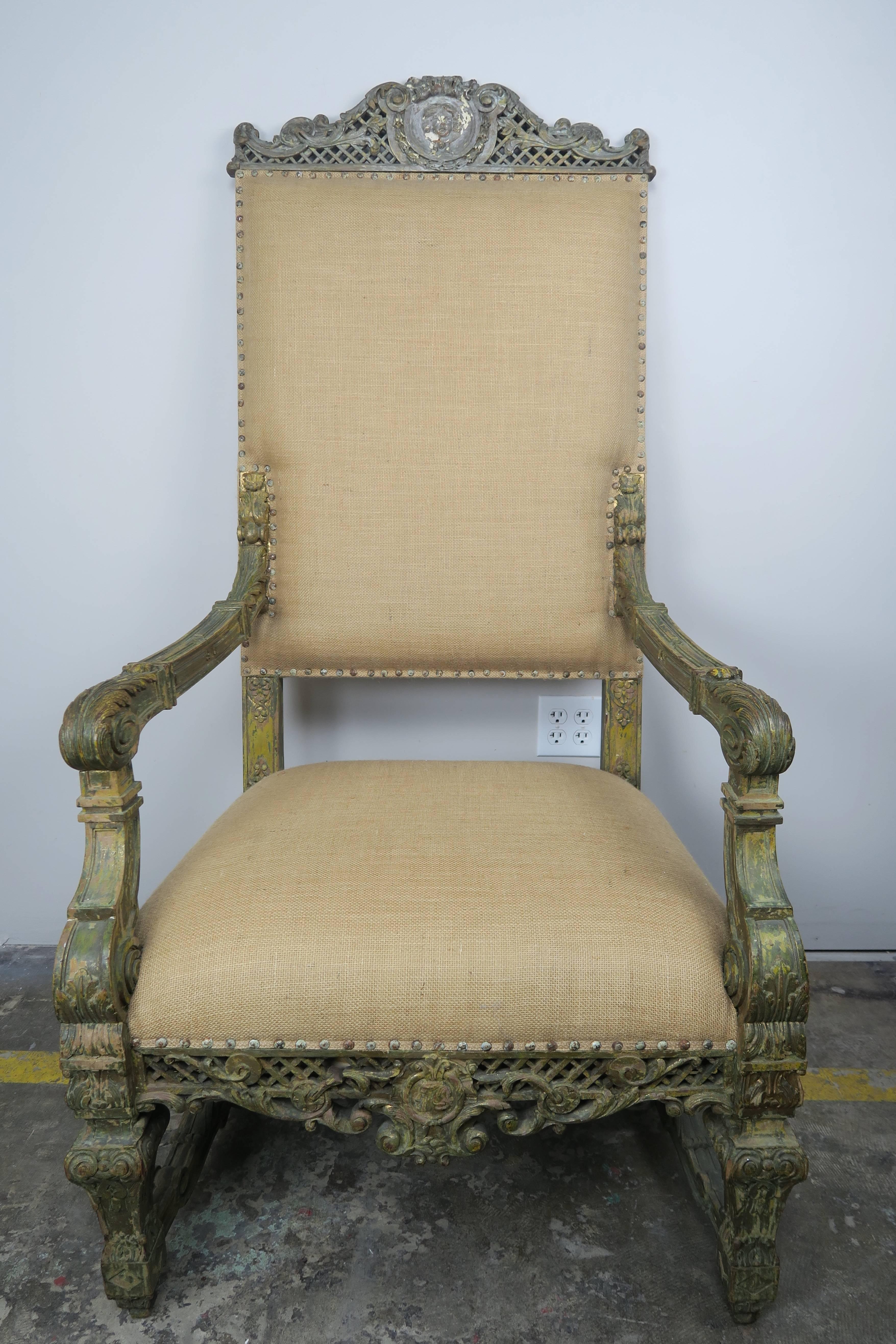 19th century monumental scaled Italian carved wood painted armchair standing on four straight legs. Ornate carving throughout the armchair. Newly upholstered in a natural burlap textile with original nailhead trim detail.