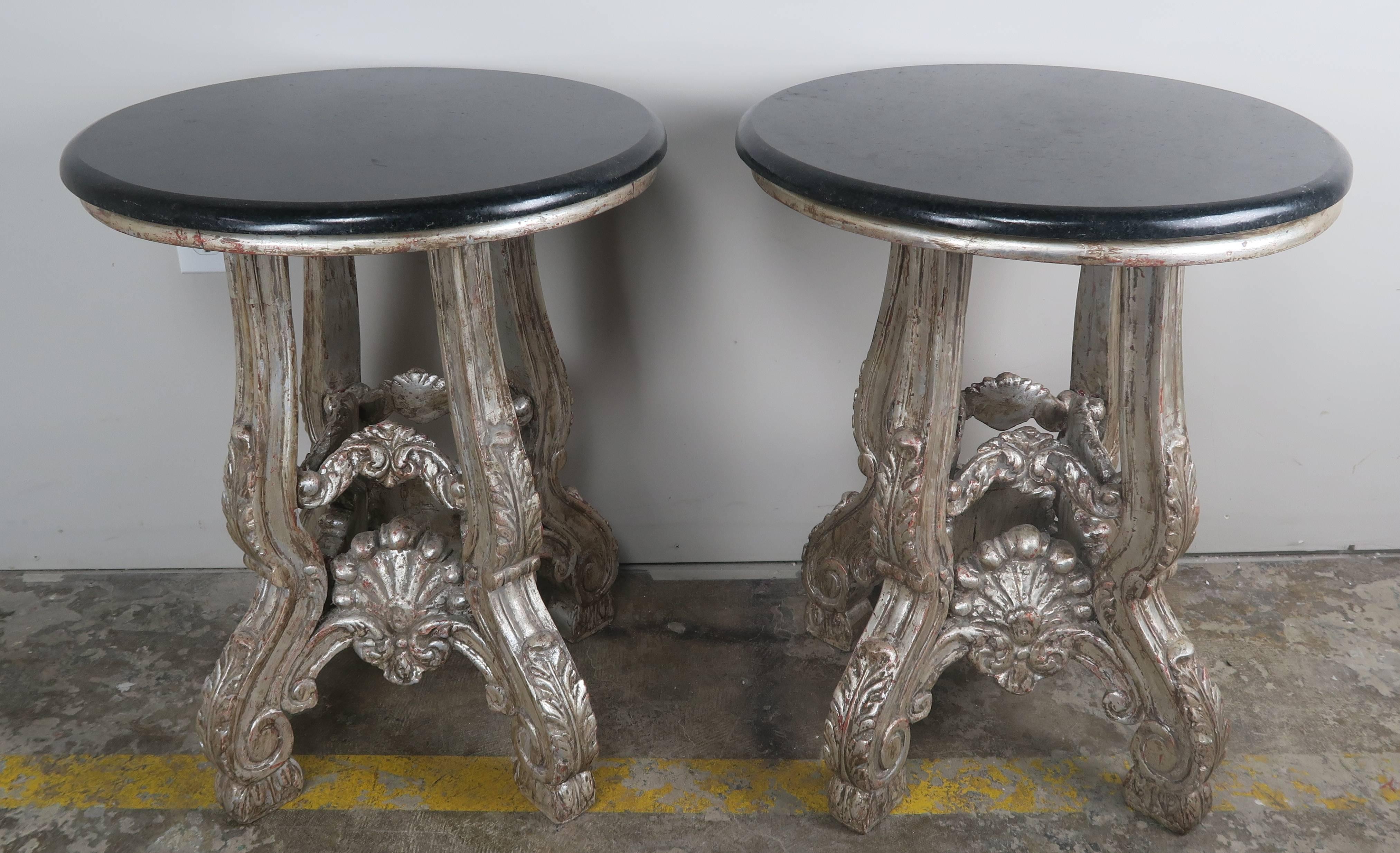 Pair of 1930s French silver leaf carved wood tables standing on four legs with acanthus leaf and scrolled details. Carved shells on all four sides. Back granite tops.