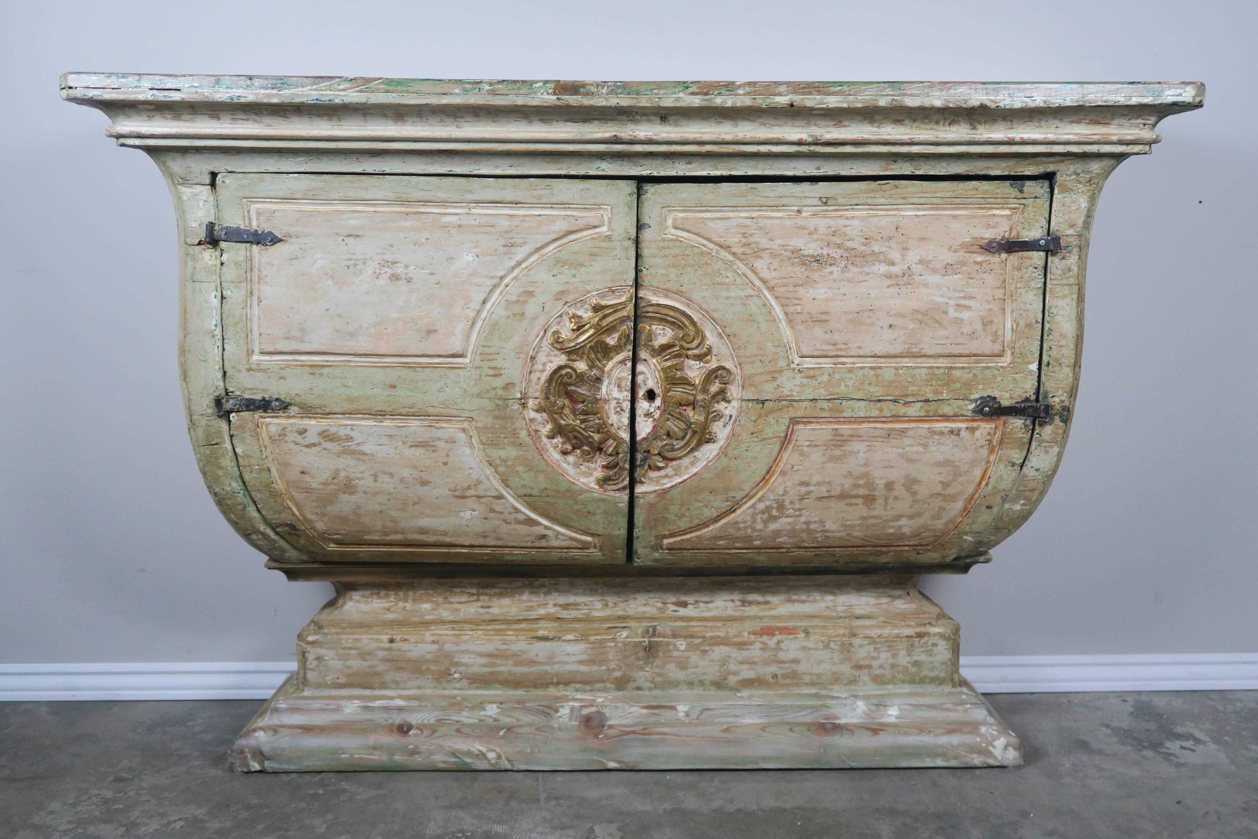 Early 19th century Italian painted and parcel-gilt console that was originally used as an alter table. The table has two doors hiding storage and one shelf behind. The console is painted a soft sea foam green and cream coloration with great wear to
