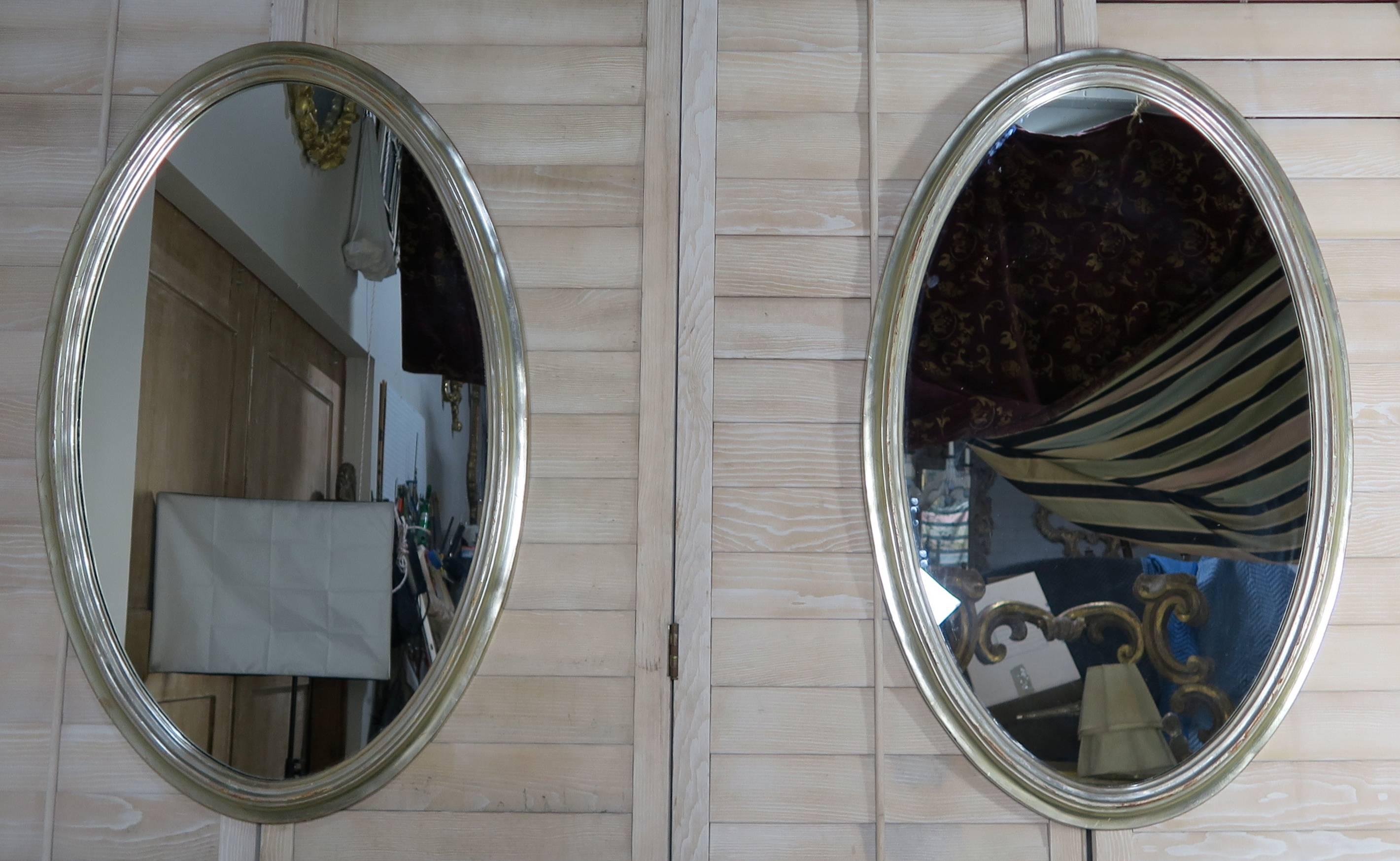 Pair of mid-century silvered oval shaped mirrors.