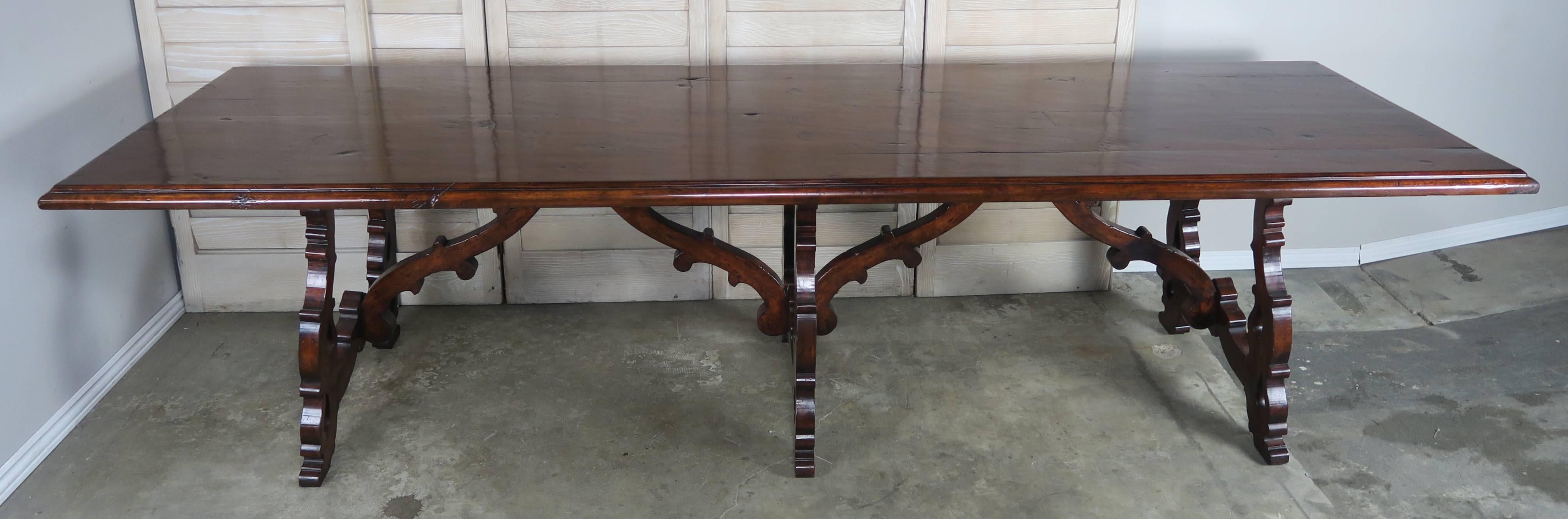 Unique Spanish Baroque style refractory dining table with a rectangular top supported by three lyre shaped bases ending in six legs. Two wooden stretchers gracefully join the three lyre shaped sections. Nice patina.