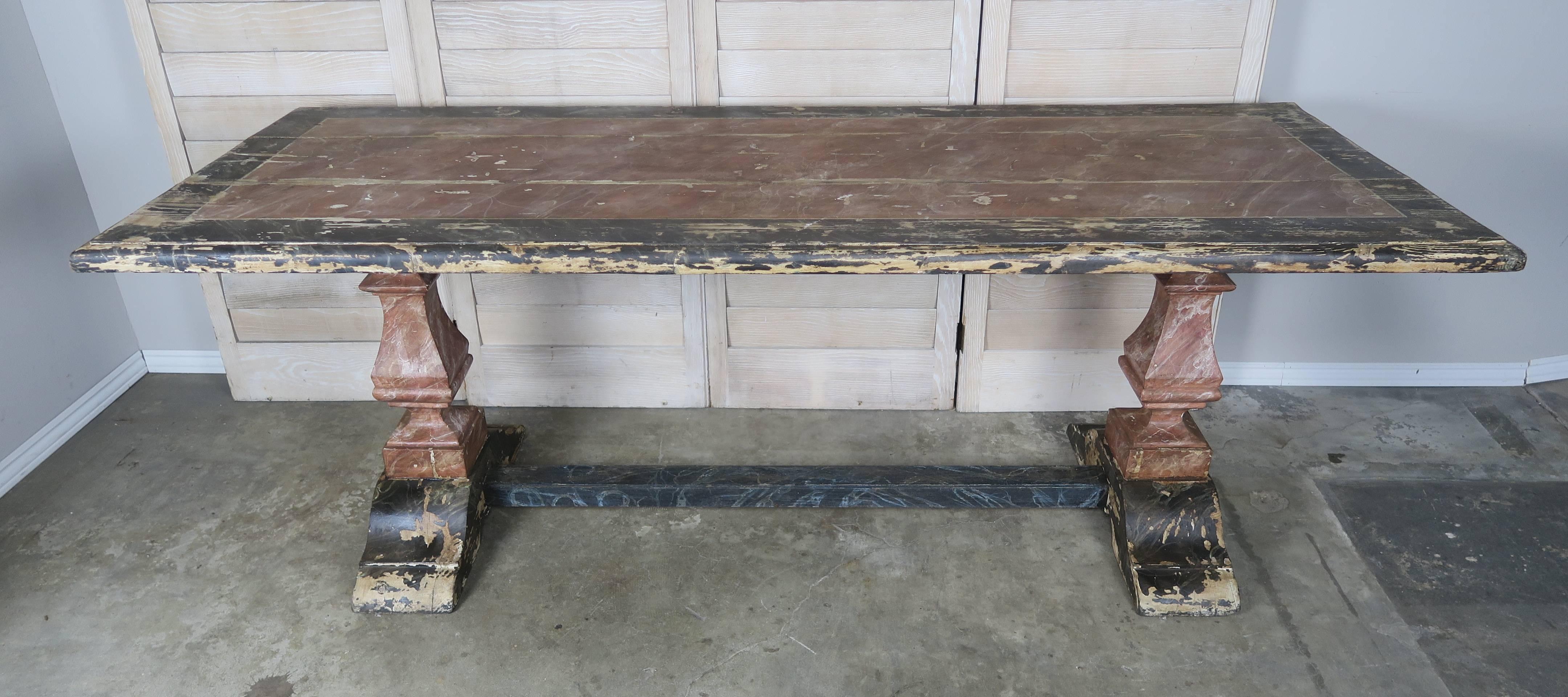 19th century Italian painted trestle table finished in a faux marble. The table stands on two heavy pedestal bases connected by a center stretcher. Worn & chipped paint throughout.