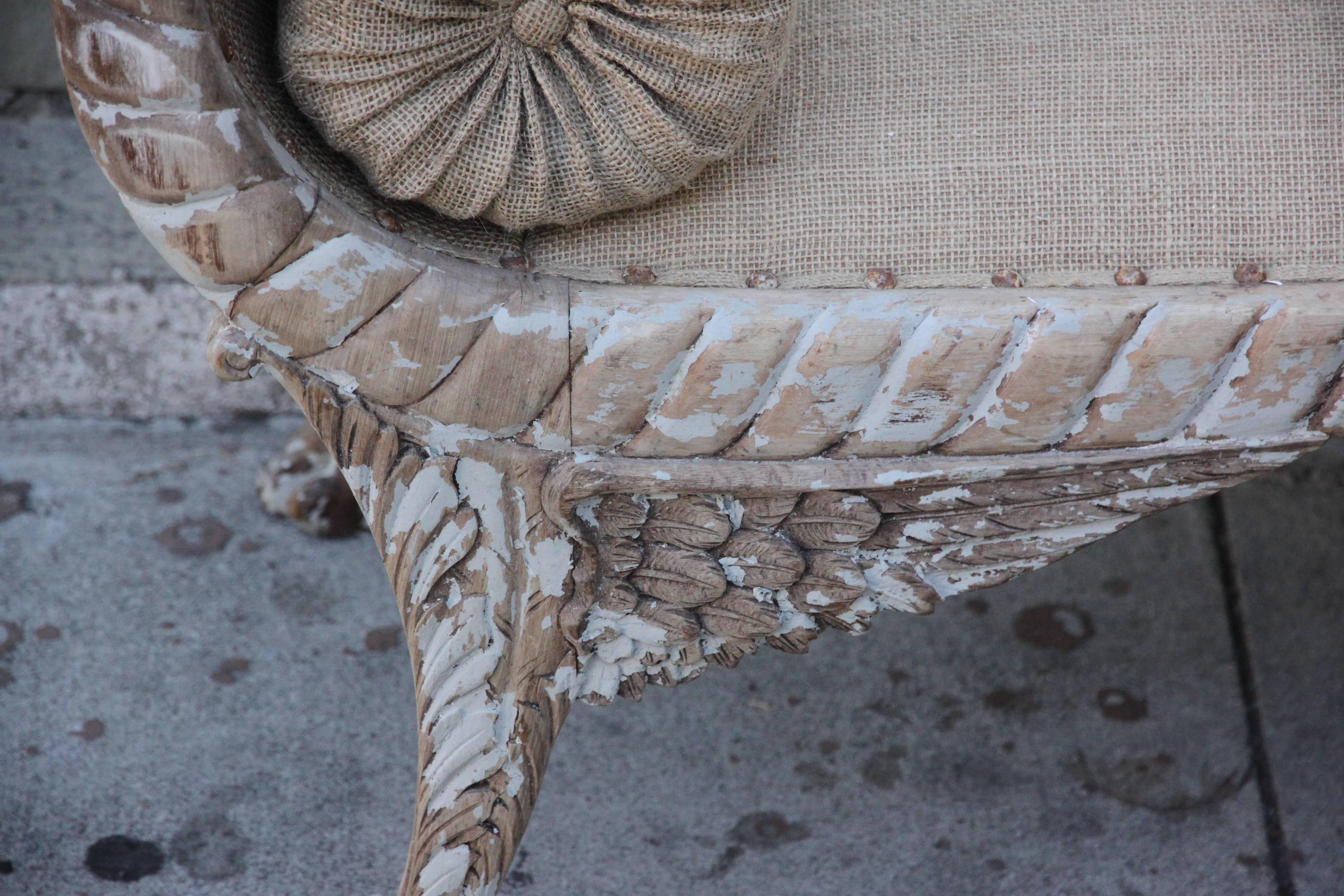 Carved painted Regency style Bench depicting cornucopias at the sides and winged legs with paw feet.  The bench is newly upholstered in burlap textile with spaced original antique nail heads.  Includes pair of burlap bolsters.