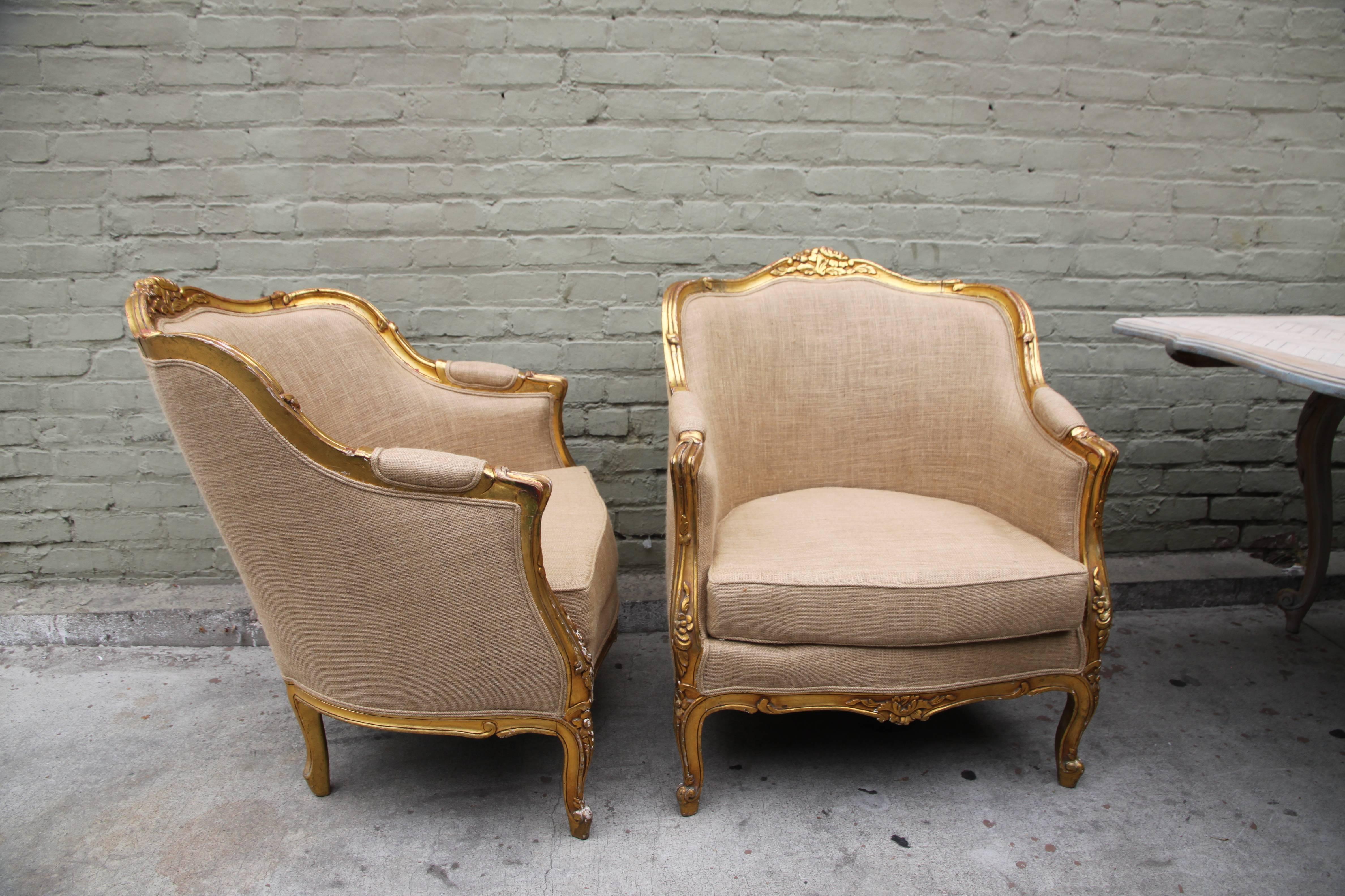 Pair of French gilt wood Louis XV style Bergeres newly upholstered in burlap with double piping self detail.