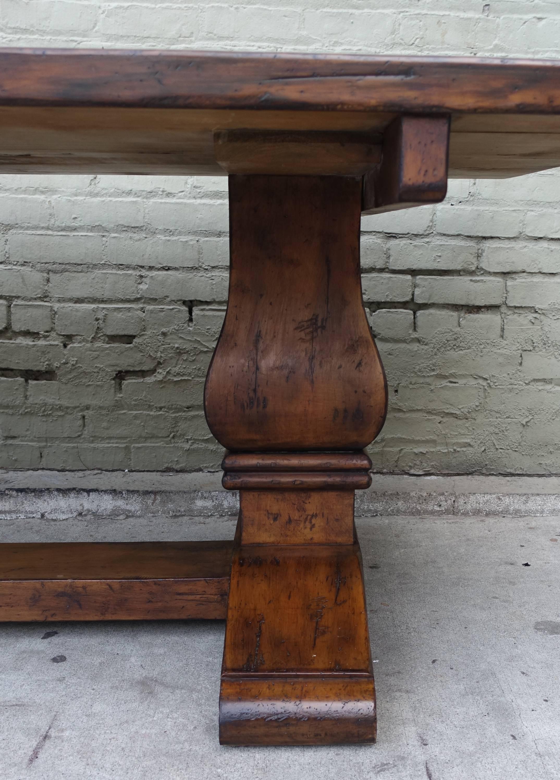 Carved walnut dining table standing on pedestals with a stretcher down the center of the table. Beautiful patina.