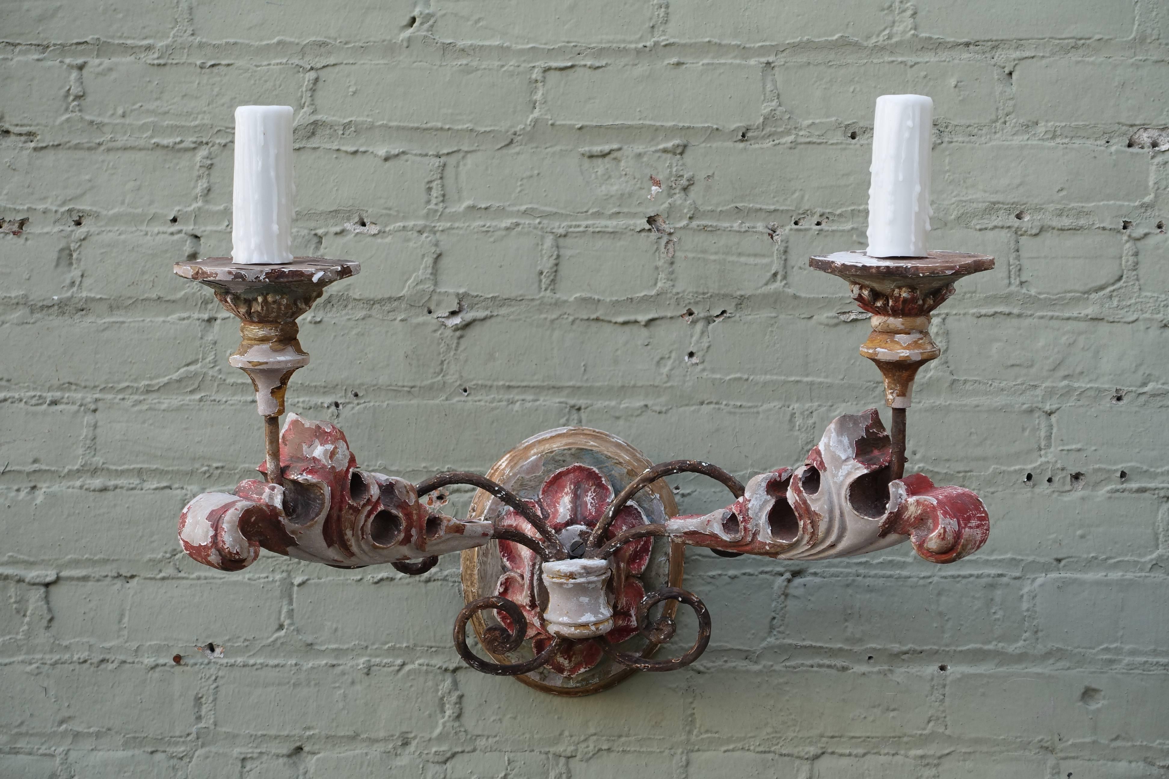 Pair of Italian two-light carved wood and painted sconces with swirling acanthus leaves. The sconces have been newly wired with UL approved stickers on the back. Drip wax candle covers.