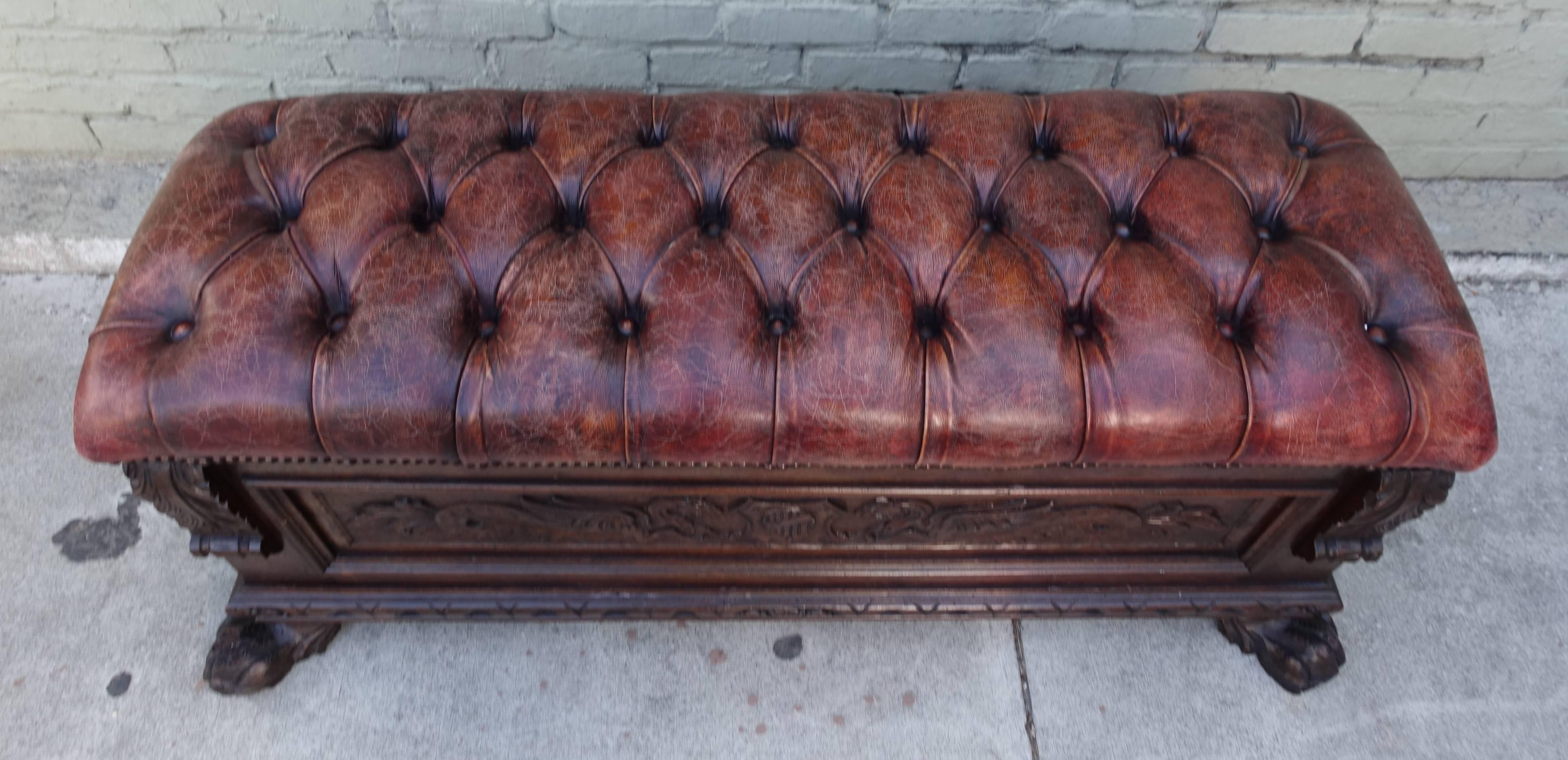 19th century Italian Renaissance style walnut cassone with a tufted leather top and nail head trim detail. The cassone is decorated with beautiful egg and dart carving and acanthus leaves along with a pair of griffins facing each other and a pair of