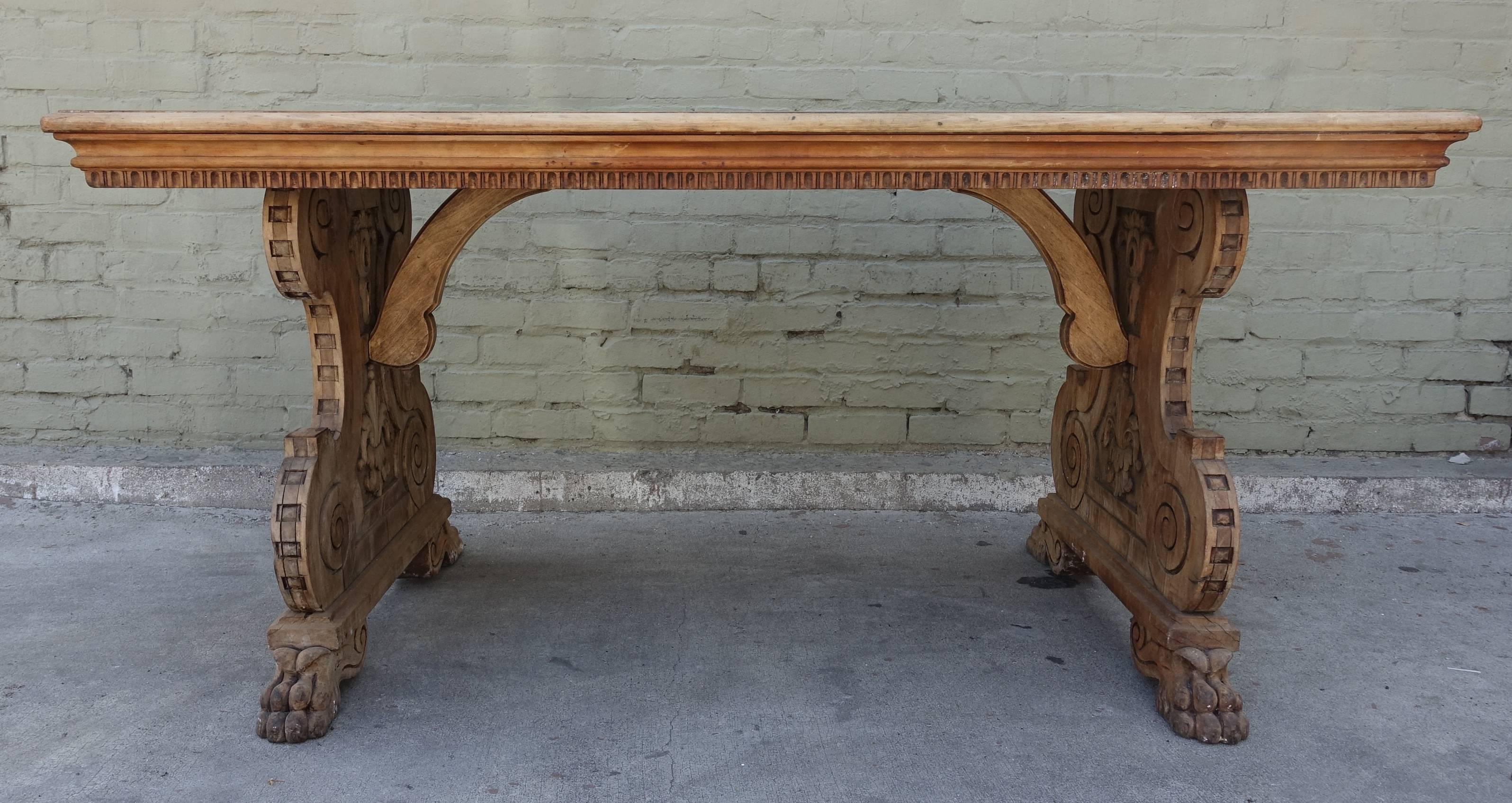 19th century carved Italian trestle style table that features floral carvings on the scrolled ends which each stand on two paw feet. Natural wood finish.