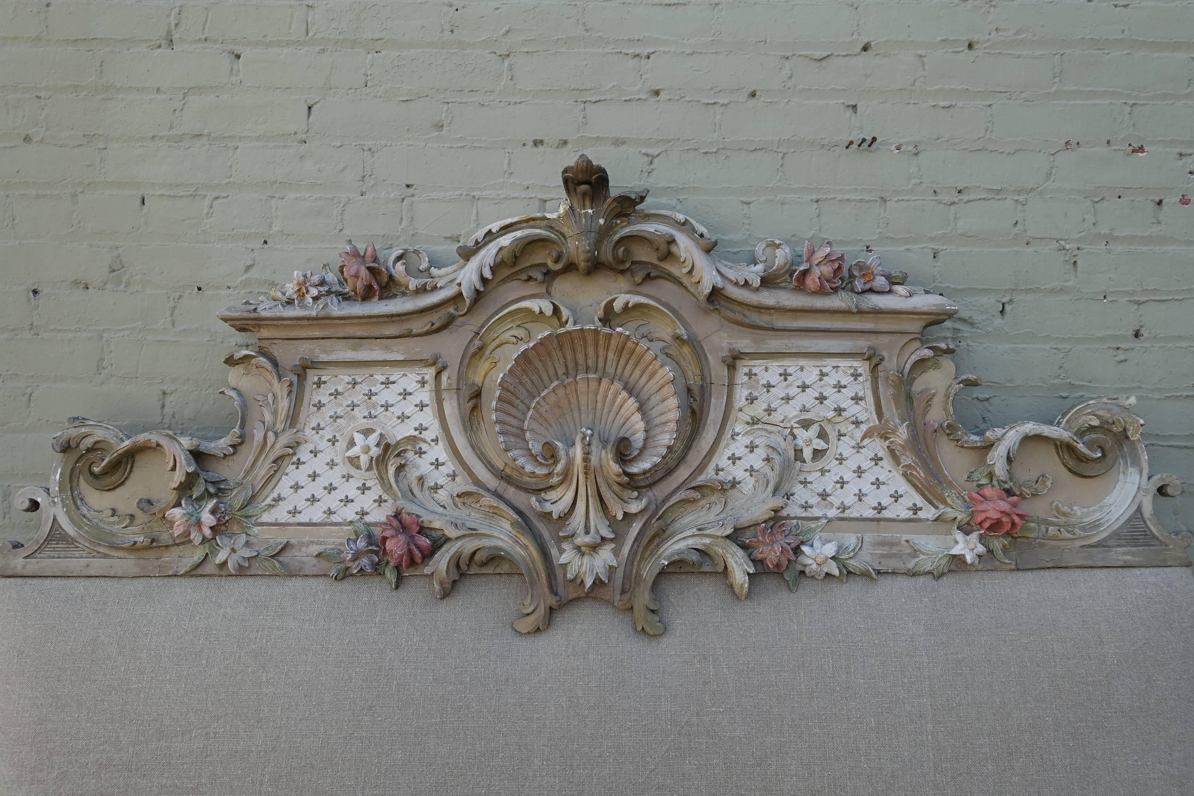 French Louis XV style carved painted headboard with new Belgium linen upholstery. Center cartouche embodies a large shell and the carved portion is adorned with swirling acanthus leaves throughout.