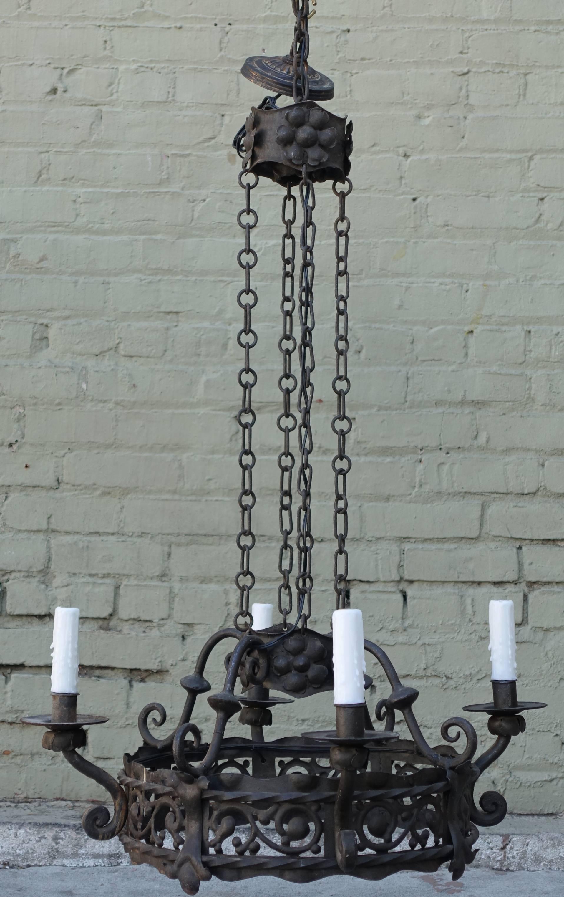 Spanish four-light hand-wrought iron chandelier suspended from four iron chains. Drip wax candle covers. Newly wired and ready to install.