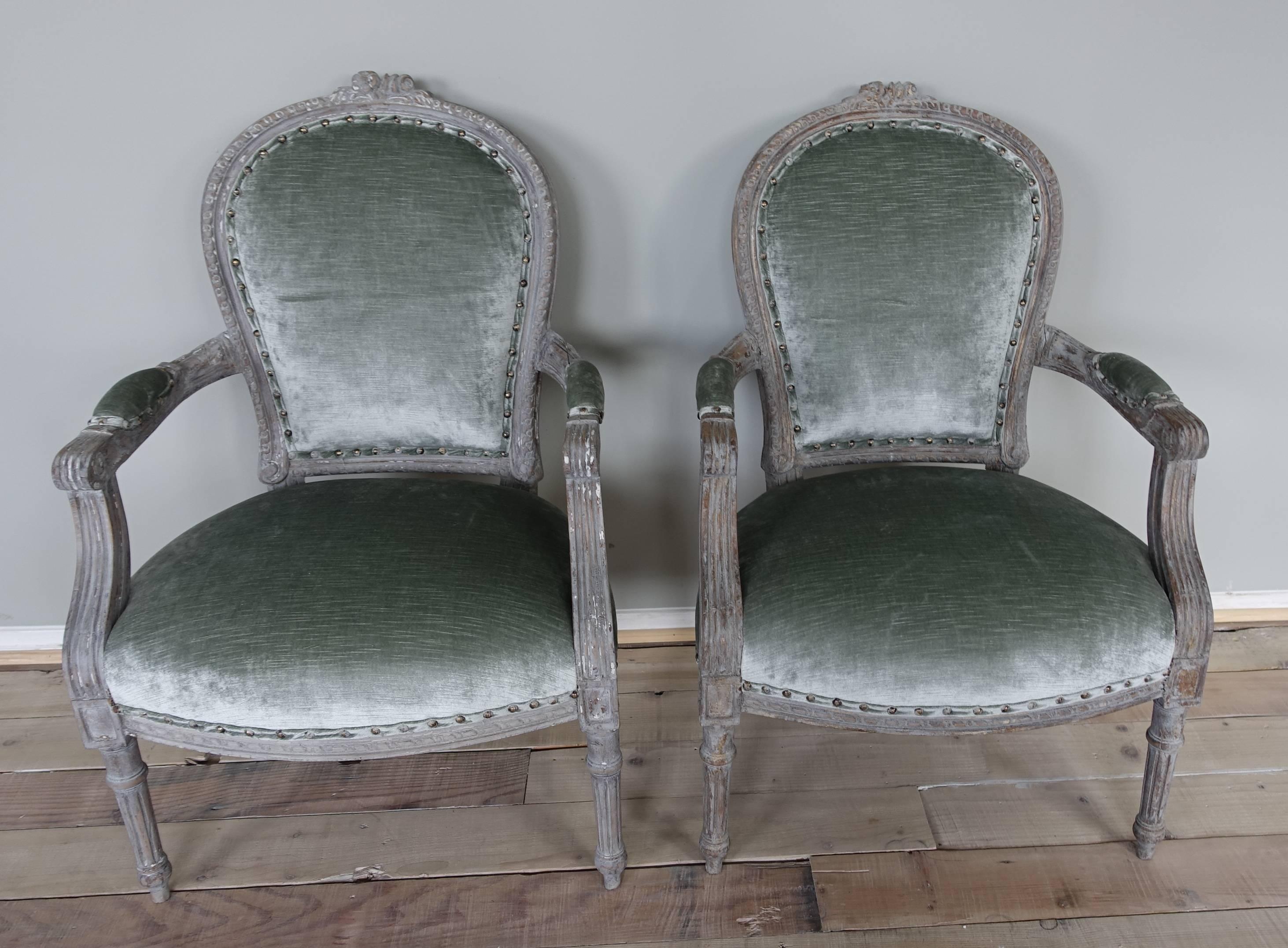 Pair of neoclassical style French painted armchairs newly upholstered in sea foam colored linen velvet with self welt and spaced nailhead trim detail. The chairs Stand on four straight fluted legs.