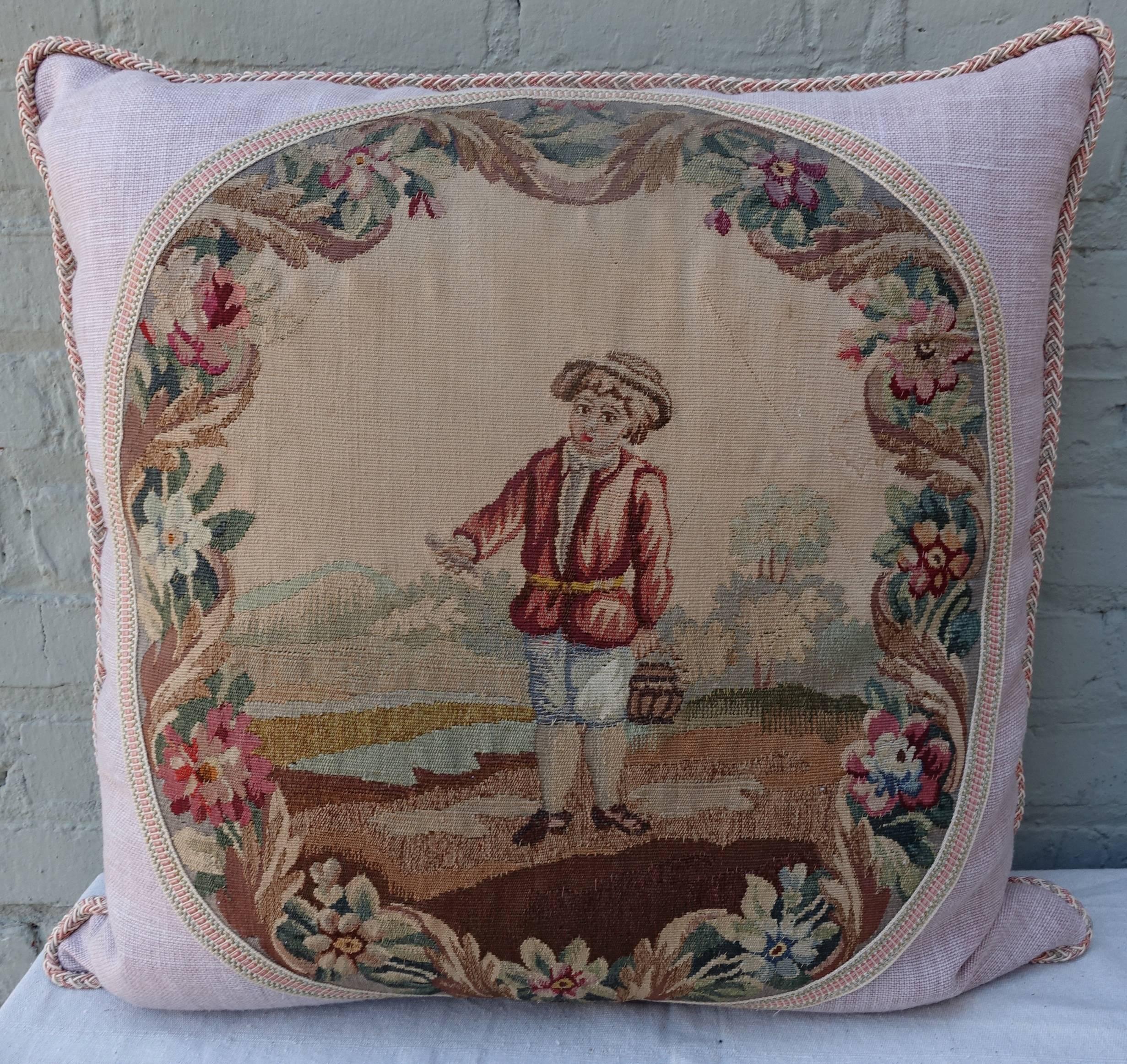 Pair of custom designed pillows made from 19th century French Aubusson figural tapestries (boy and girl) combined with a soft textured pink petal colored linen and detailed with a contrasting multicolored cording and tape. Down insert. Designed by