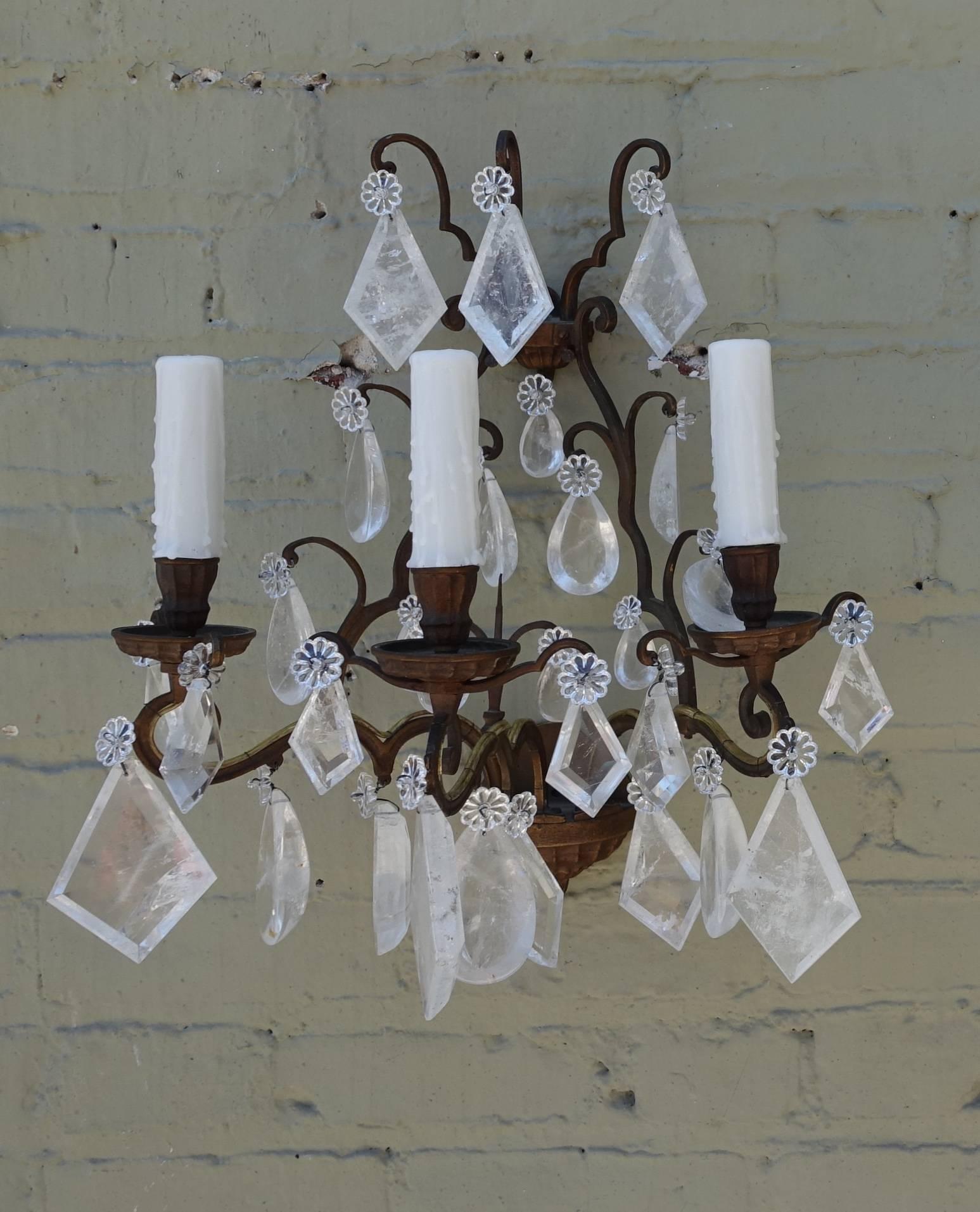Pair of three-light bronze rock crystal sconces with drip wax candle covers. The sconces are adorned with a combination of kite shaped rock crystals and almond shaped rock crystals. The pair of sconces has been newly rewired with white drip wax
