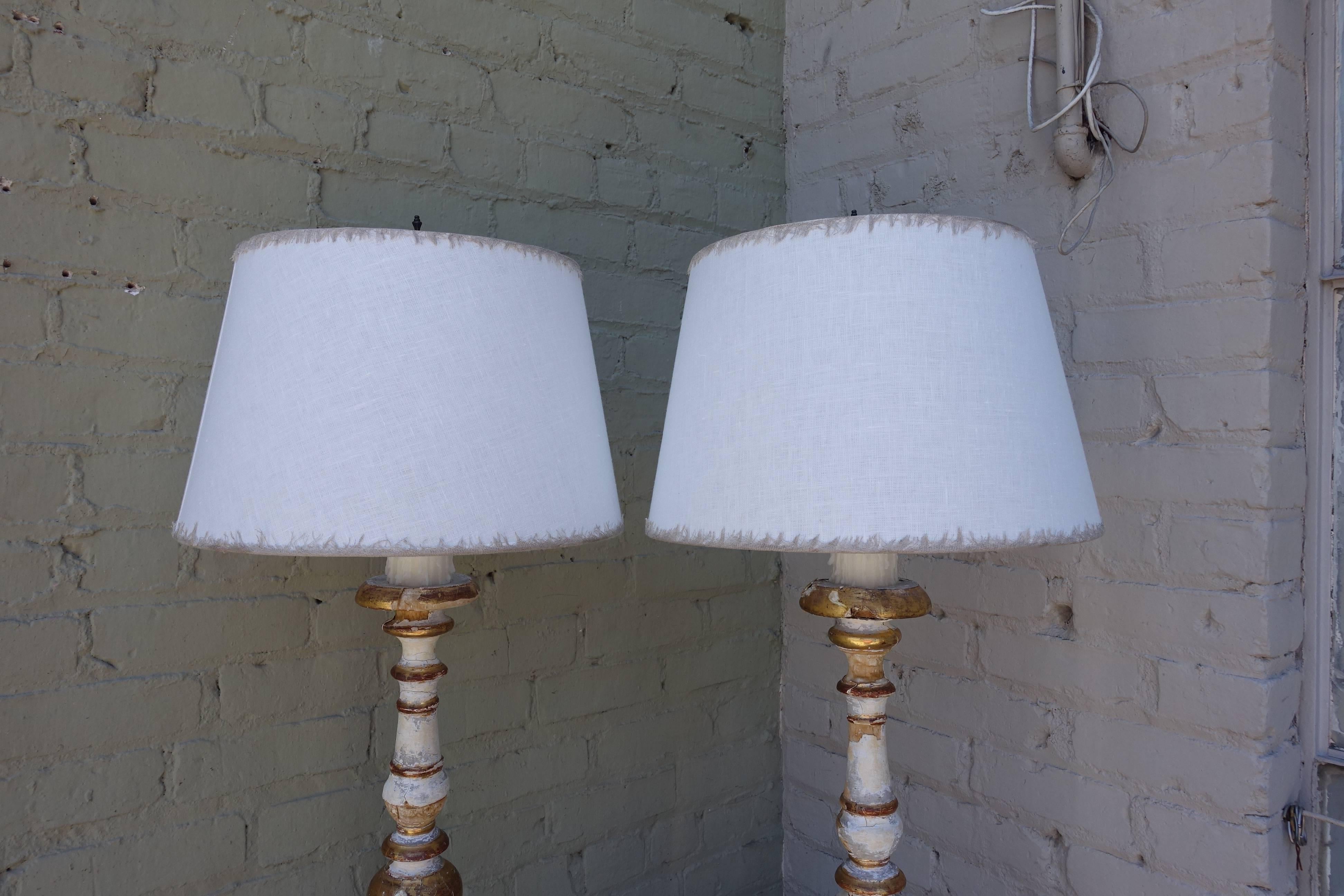 Pair of 19th century Italian painted and parcel gold gilt candlesticks wired into lamps and crowned with custom white linen shades with eyelash trim detail.