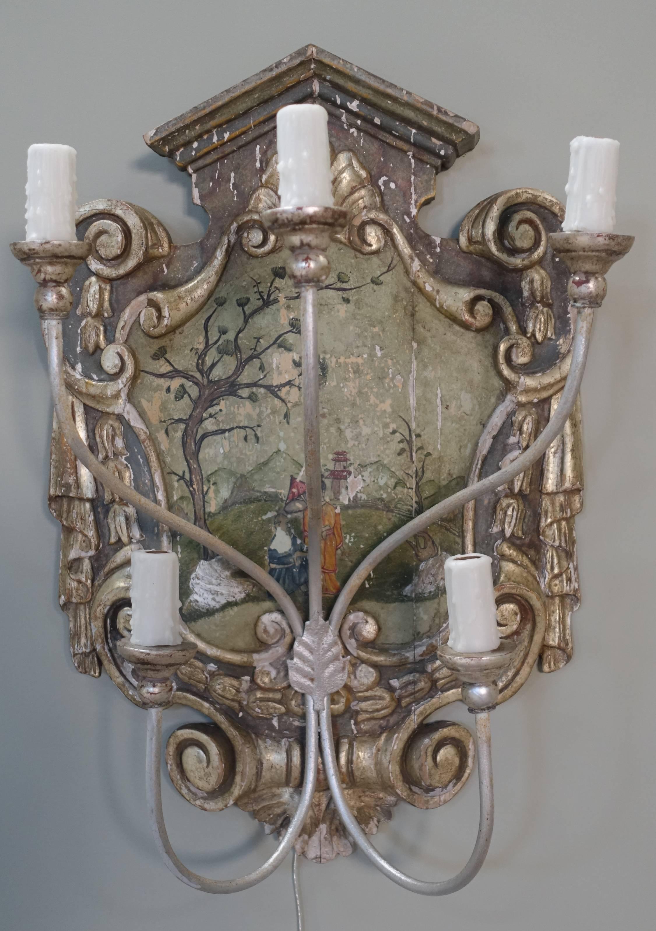 Pair of hand-painted pagoda shaped wood carved painted and parcel-gilt sconces with detailed chinoiserie design in center. The sconces are newly rewired with drip-wax candle covers. Silver giltwood bobeches and silver gilt metal arms.