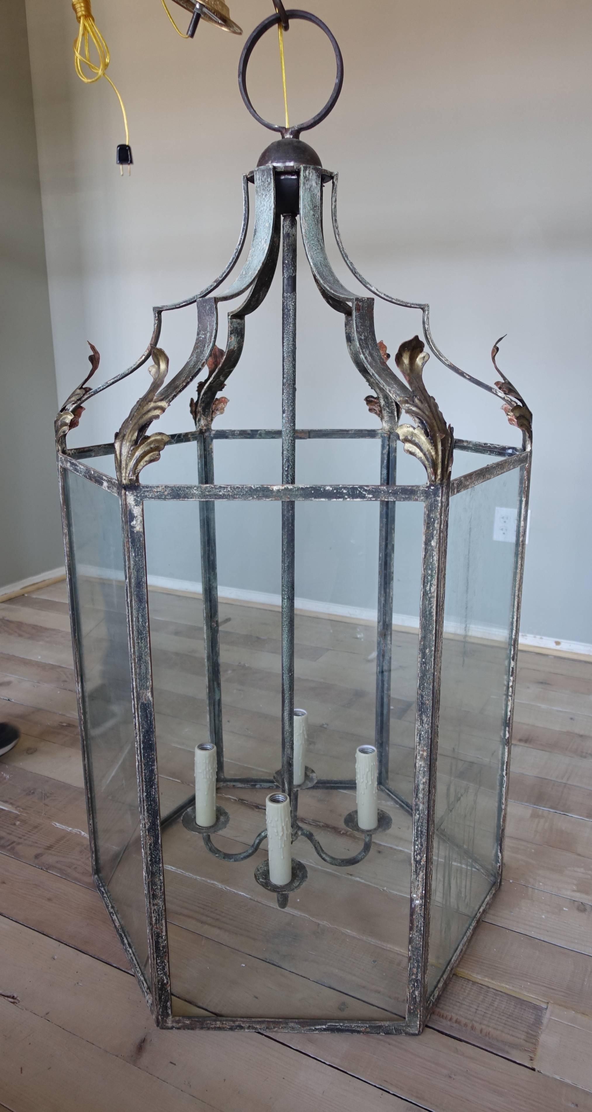 Monumental Italian wrought iron four-light lantern with gilt metal acanthus leaf detail. Distressed finish. Newly rewired with chain and canopy included.