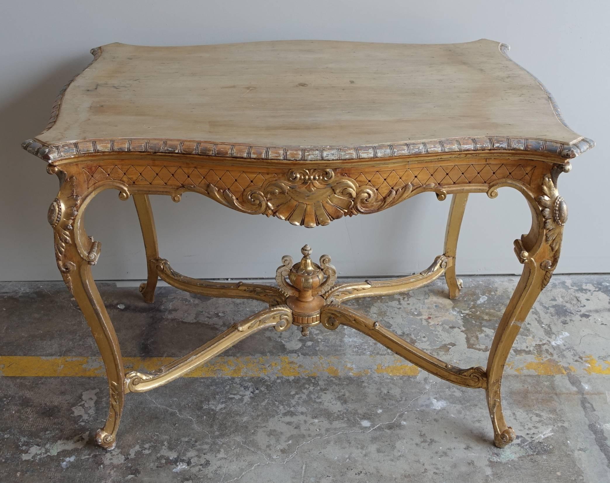 19th century French Louis XV style wood table standing on four cabriole legs that turn into rams head feet. Four acanthus leaf decorated stretchers meet at a center urn. The cabriole leg is adorned with a carved sunflower on all four corners. Shell