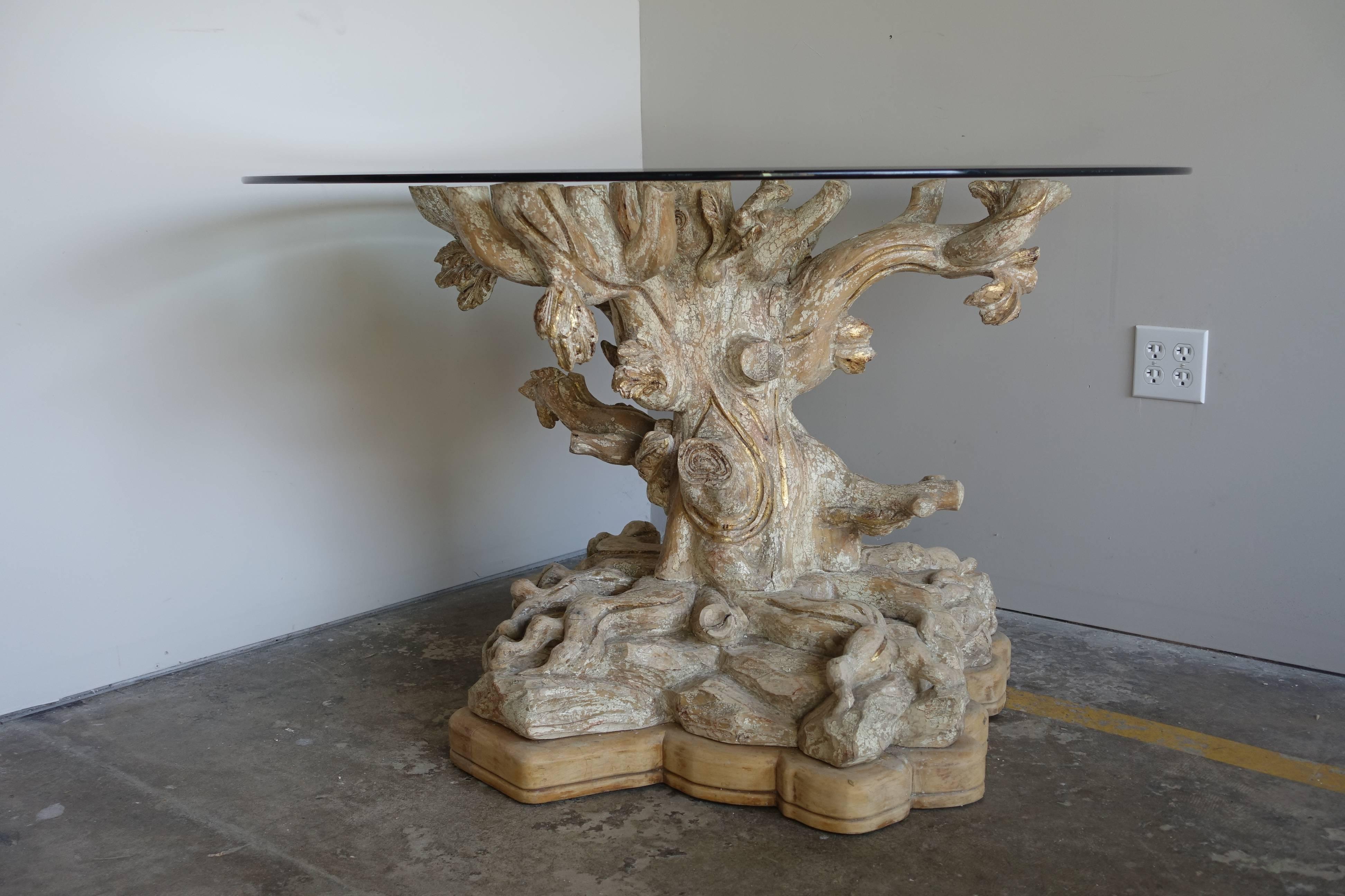 Italian carved painted and parcel-gilt tree trunk table with a beveled glass top.