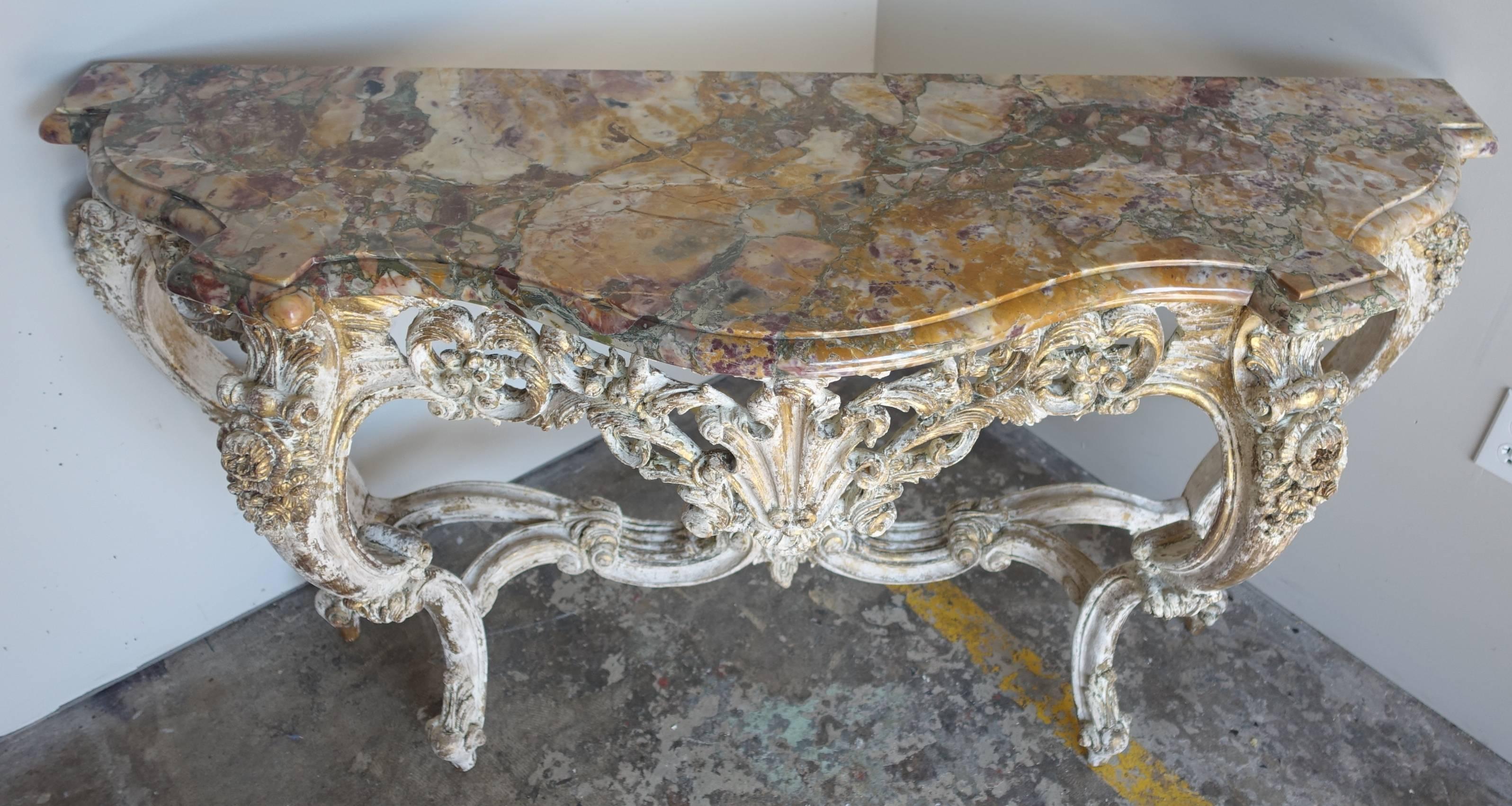 Pair of 19th century French Louis XV style painted and parcel gilt consoles with a carved shell, acanthus leaves, and roses throughout. Original marble tops.