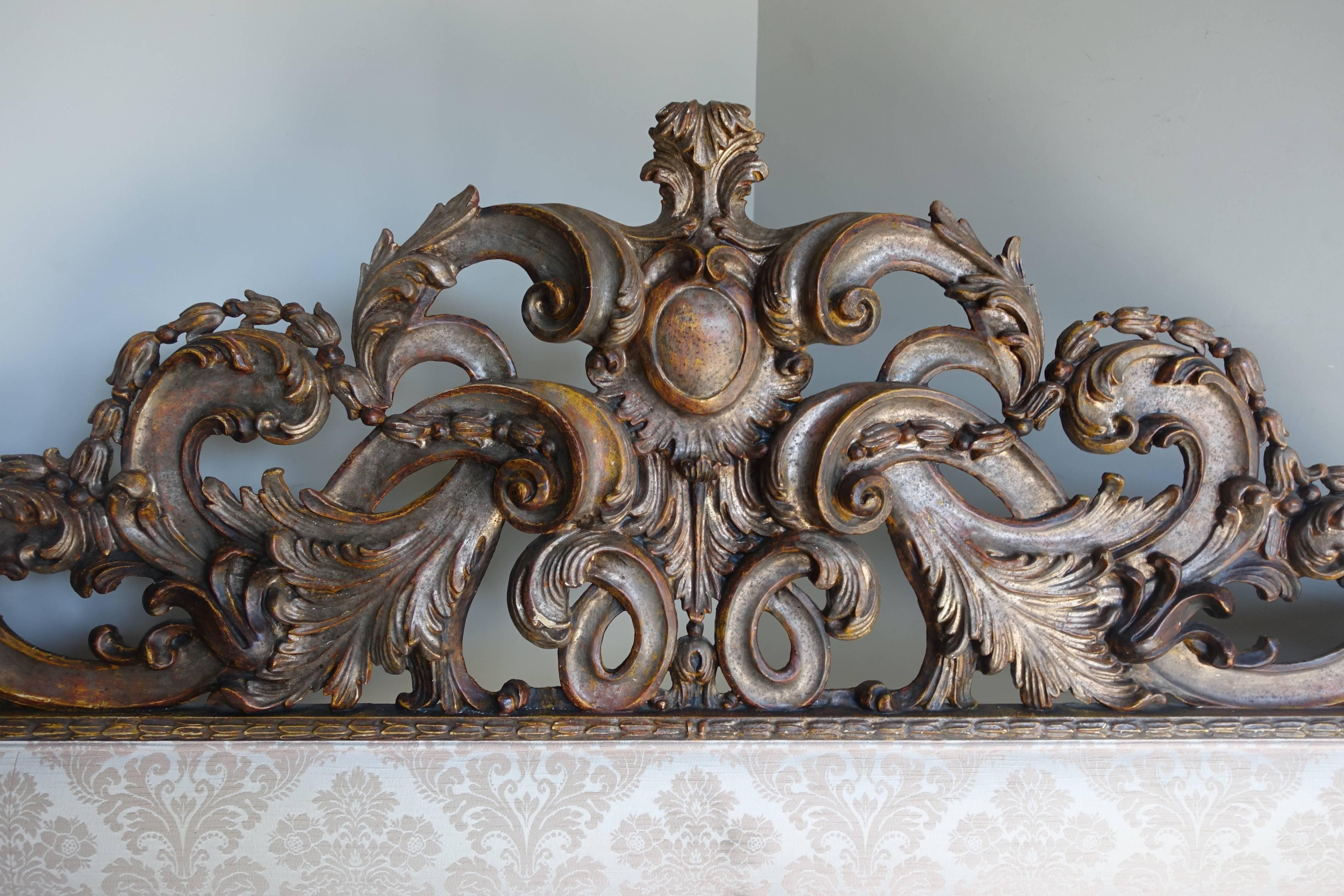 Italian carved headboard with a beautiful worn borghese finish combining soft faded paint with faded silvery gold highlights. Upholstered in a cream colored floral damask that can be easily changed to go with your decor.