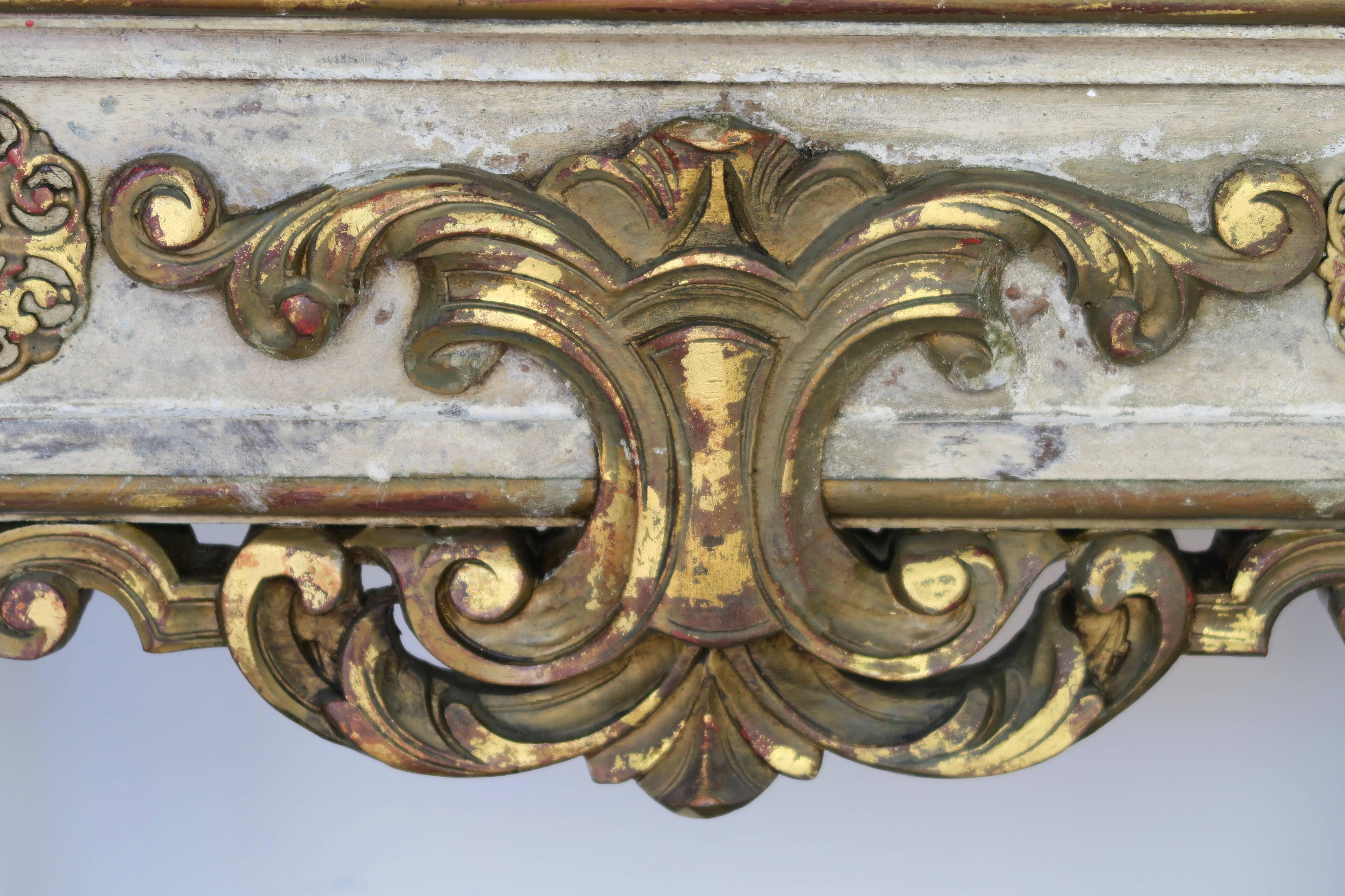 Italian painted and parcel gilt neoclassical style console standing on four fluted columns mounted on V-shaped wood base. Carved giltwood acanthus leaf carving at center of apron. Antiqued gold mirrored inset top.