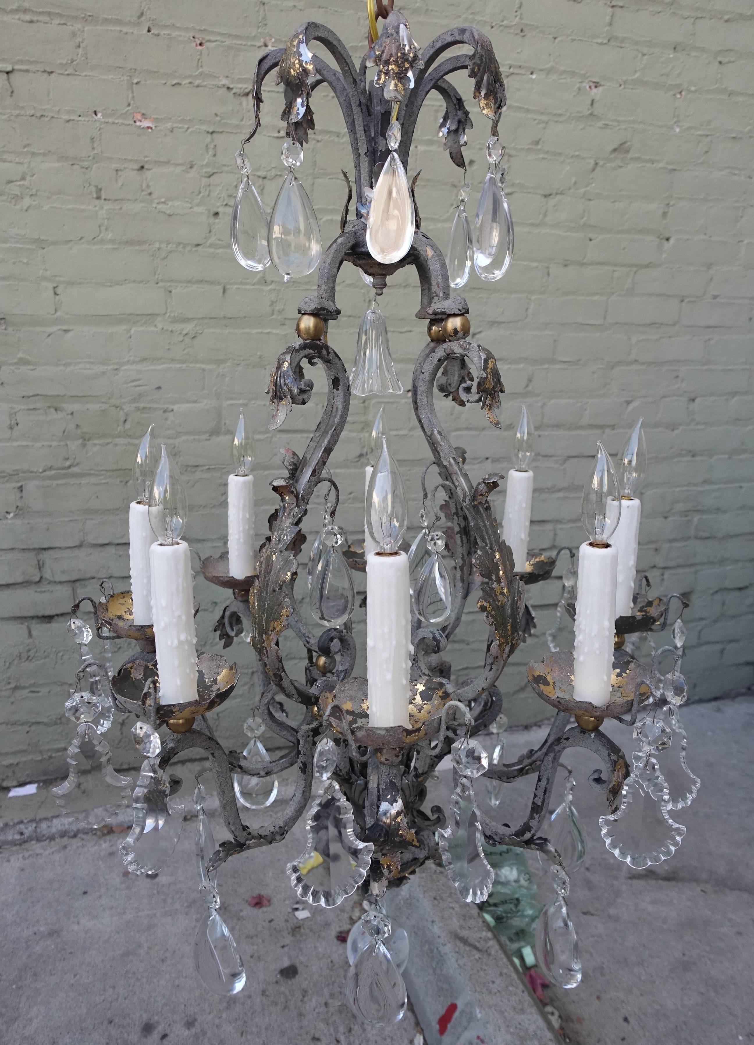 French eight-light painted wrought iron chandelier adorned with beautiful crystal drops throughout. Gold leaf can be seen underneath the paint. The chandelier has been newly rewired with drop wax candle covers.