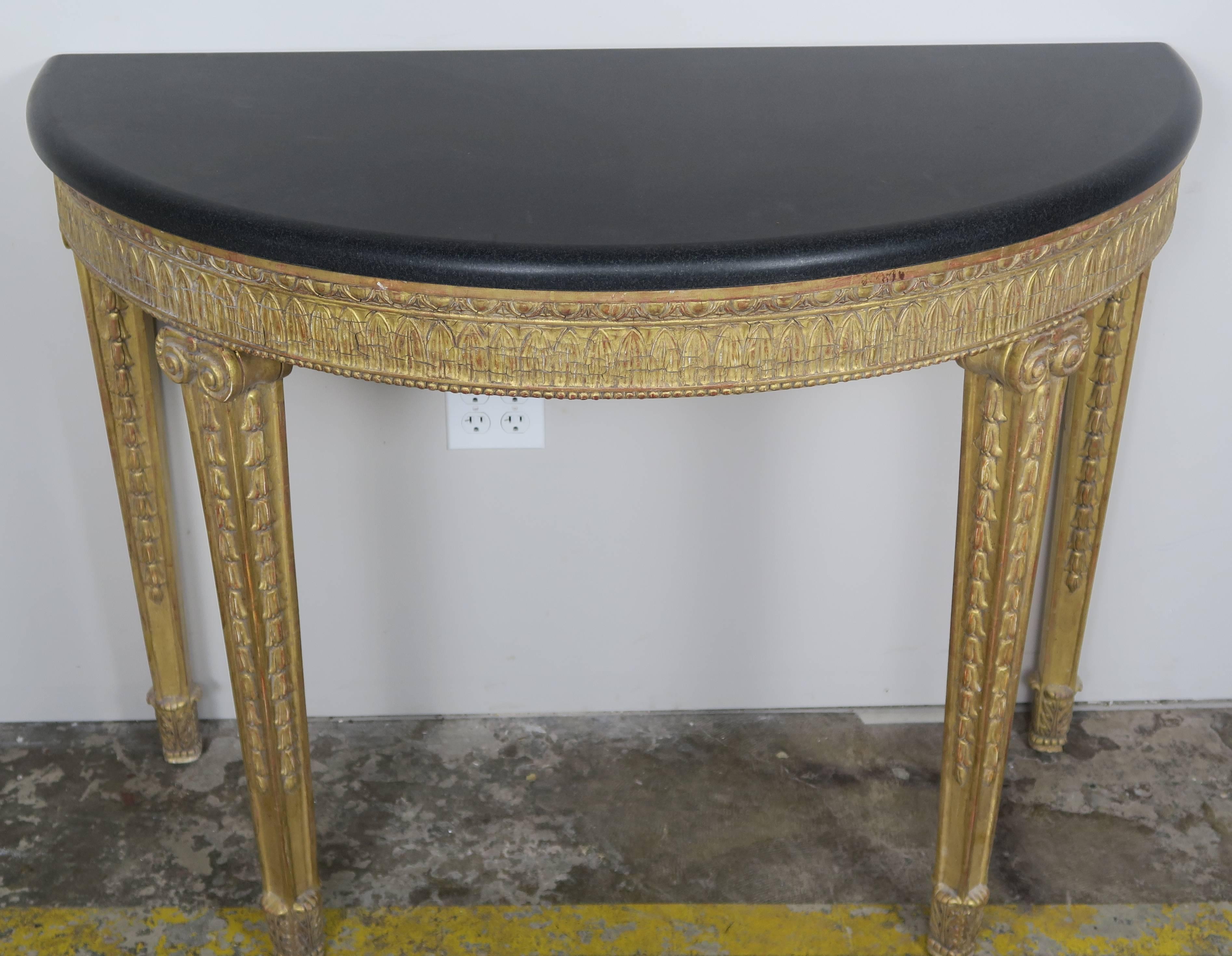 Italian neoclassical style 22-karat gold leaf carved console standing on four straight legs with a black stone top. Egg and dart carved details across the apron of the console. Bullnose edge detail on black marble-top.