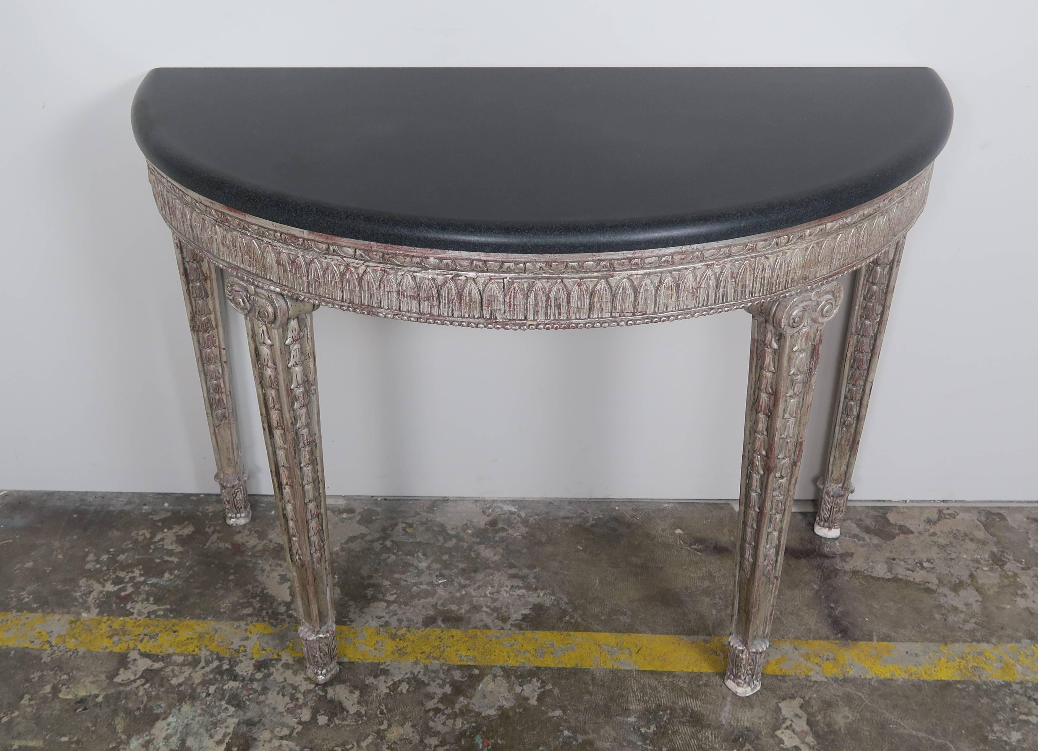 Italian neoclassical style silver gilt carved console standing on four straight legs with a black stone top. Egg and dart carved details across the apron of the console. Bullnose edge detail on black marble top.