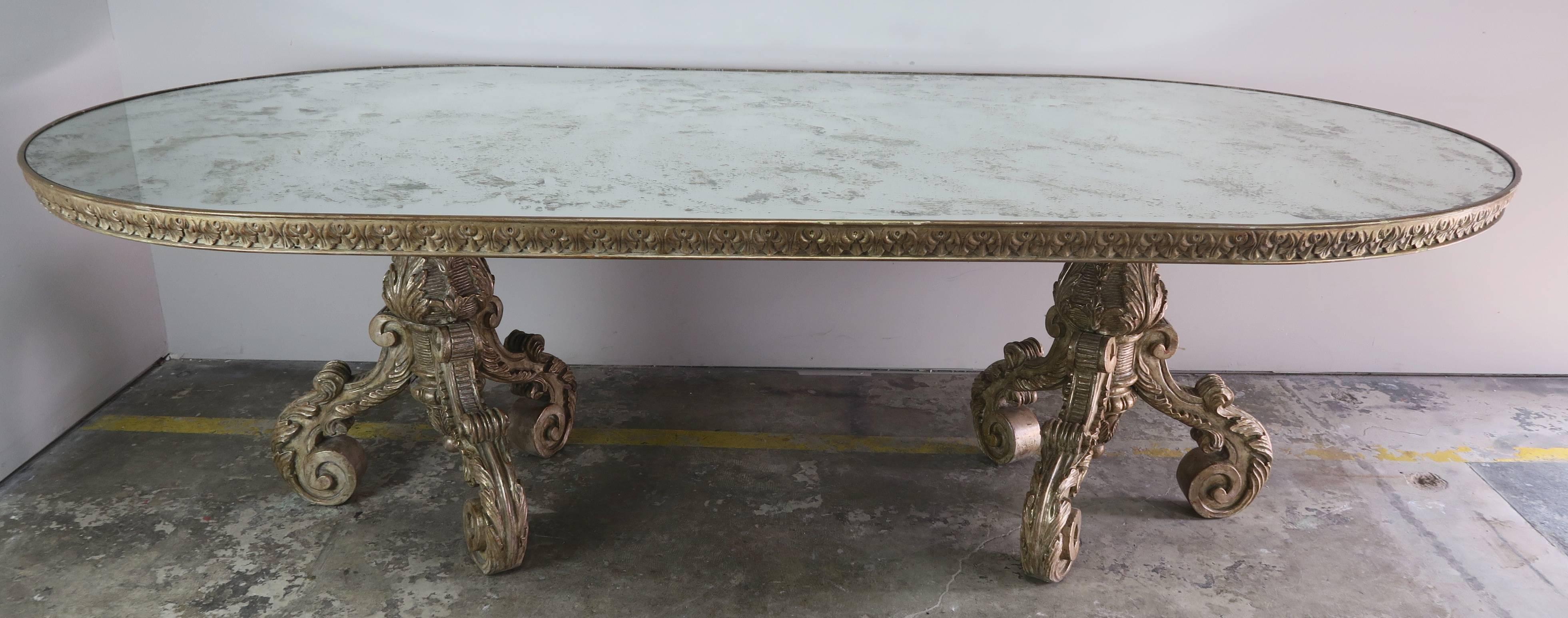 Italian carved Borghese silvered double tripod base dining table with antiqued mirrored race track shaped top.