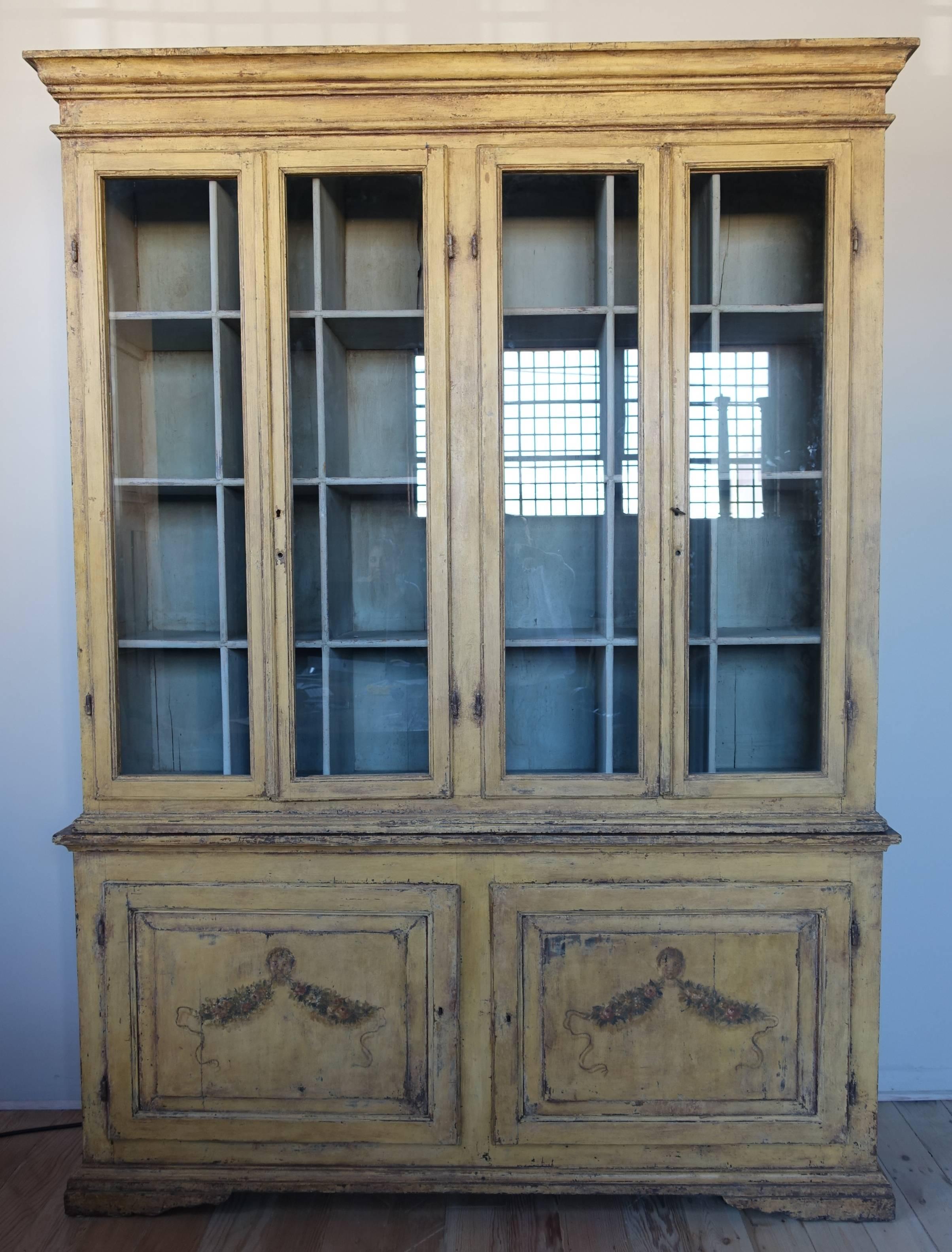 19th century hand-painted soft golden colored cabinet with painted garlands. Two storage doors with shelve on the bottom of the cabinet. Original antique glass.