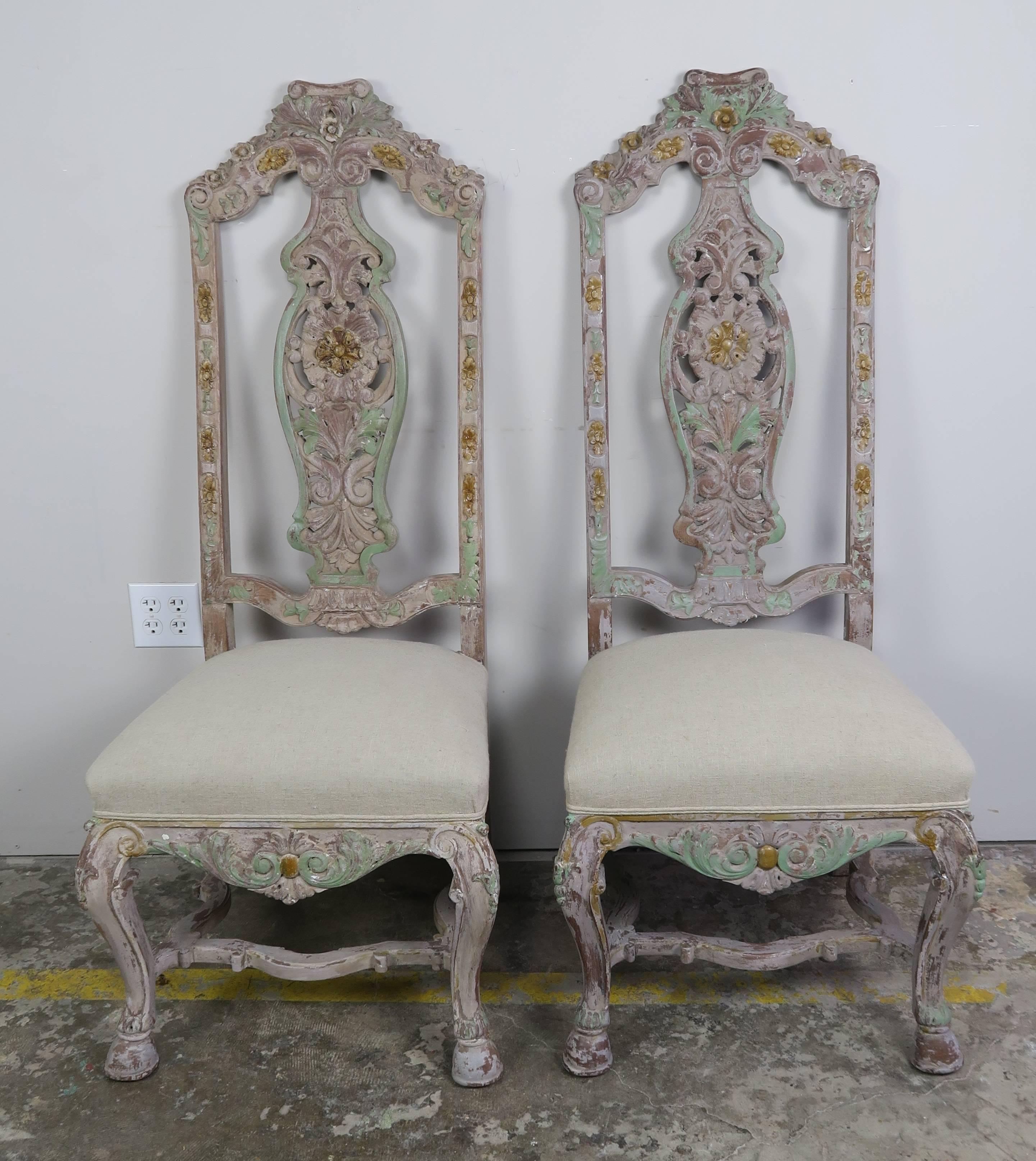 Set of 12 French painted Louis XV style dining chairs standing on cabriole legs that meet at center stretcher. Beautiful carved details throughout. Newly upholstered in a natural colored linen with self cord detail.