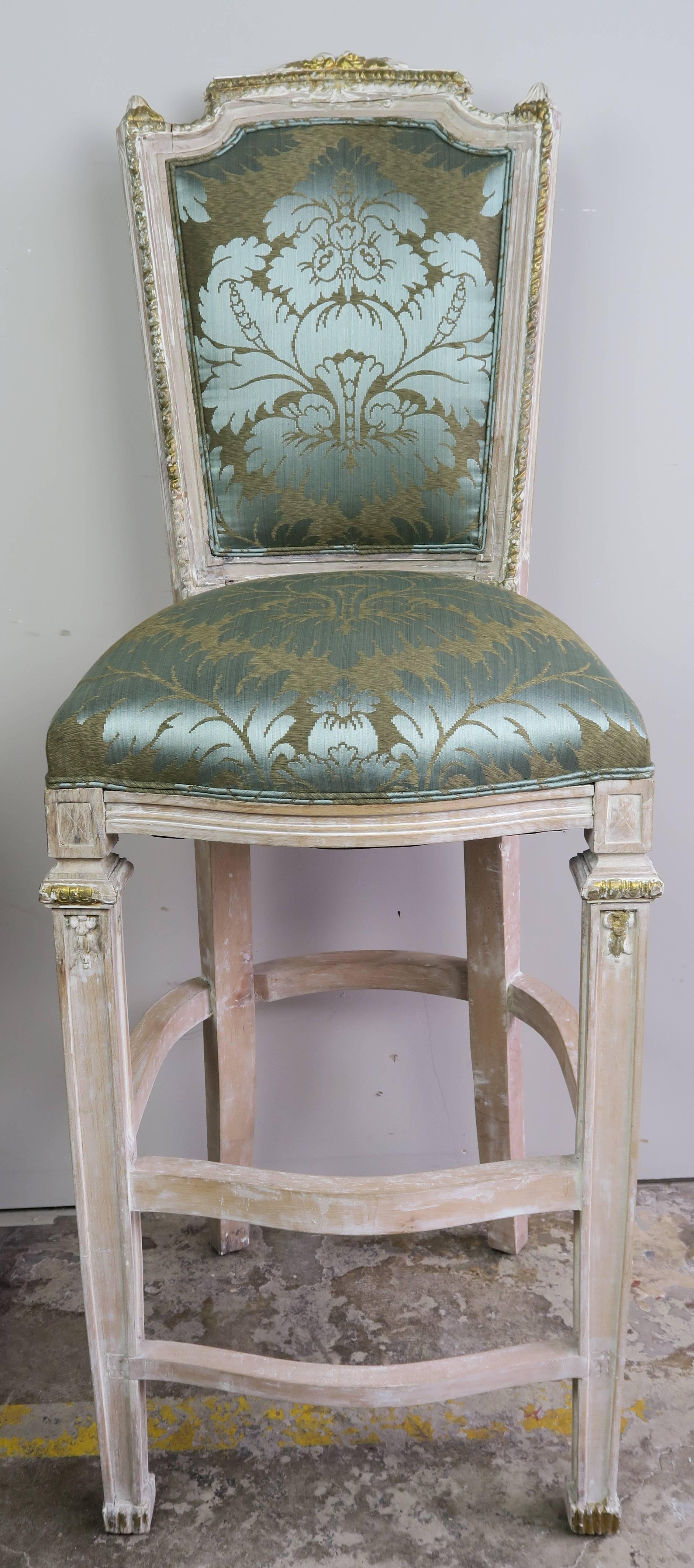 Set of three French painted and parcel-gilt Louis XVI style barstools newly upholstered in a beautiful silk damask and finished with a double self-cording.
