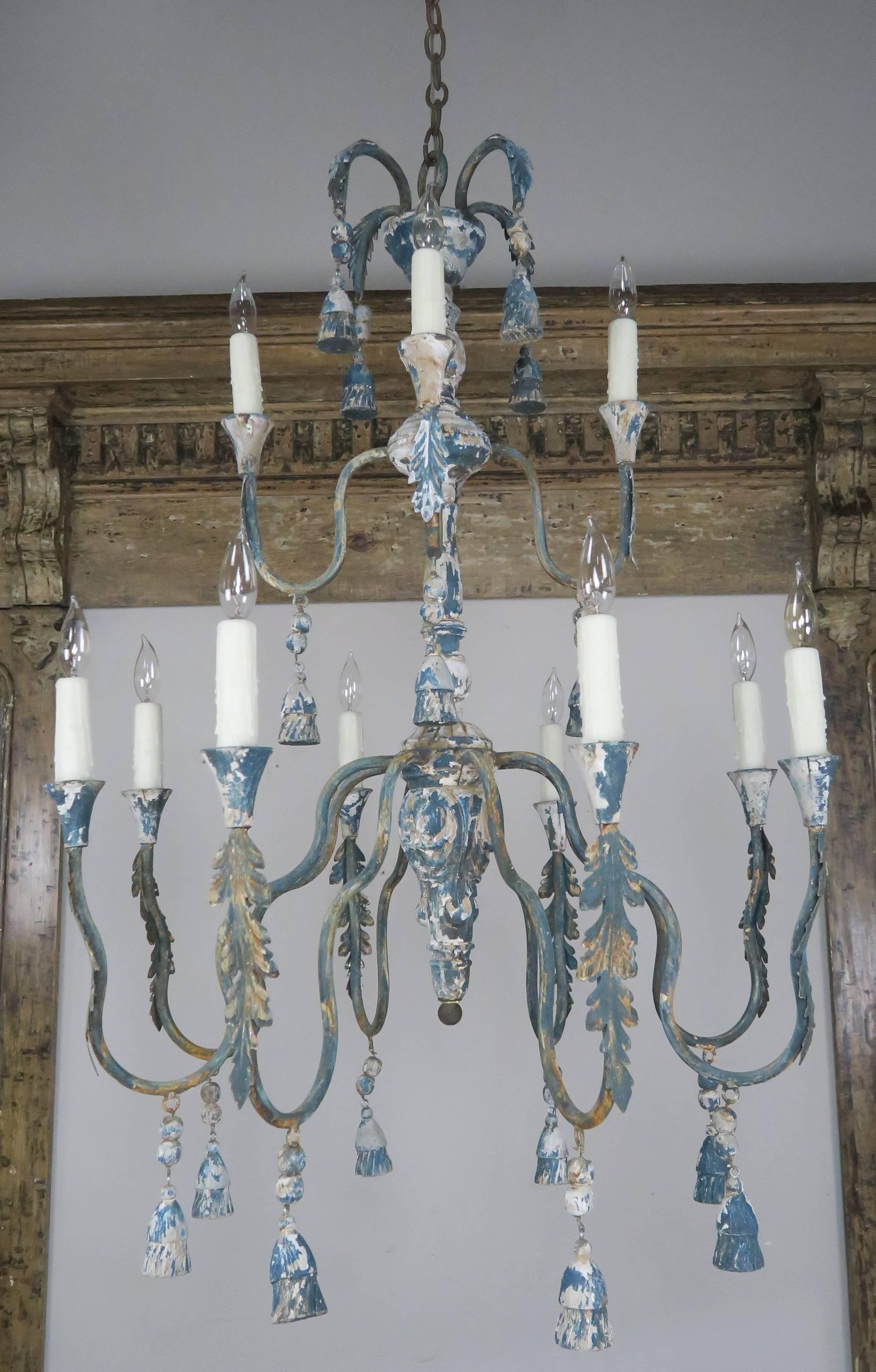 Pair of twelve-light two-tier wood and iron chandelier with carved wood tassels and iron acanthus leaf details. The fixtures have been newly rewired with drip wax candle covers. Includes chain and canopy.