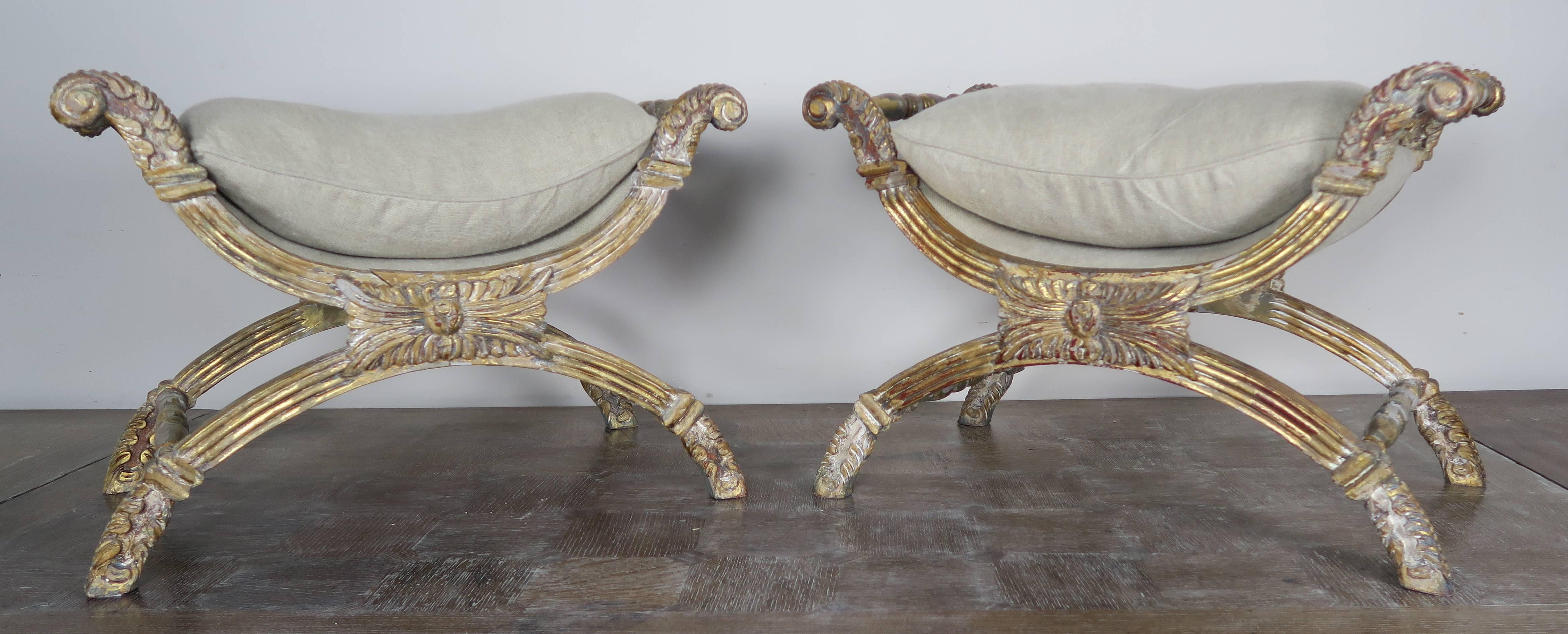 Pair of Italian giltwood X-benches with loose down filled Belgium linen upholstered cushions. Carved acanthus leaves throughout.