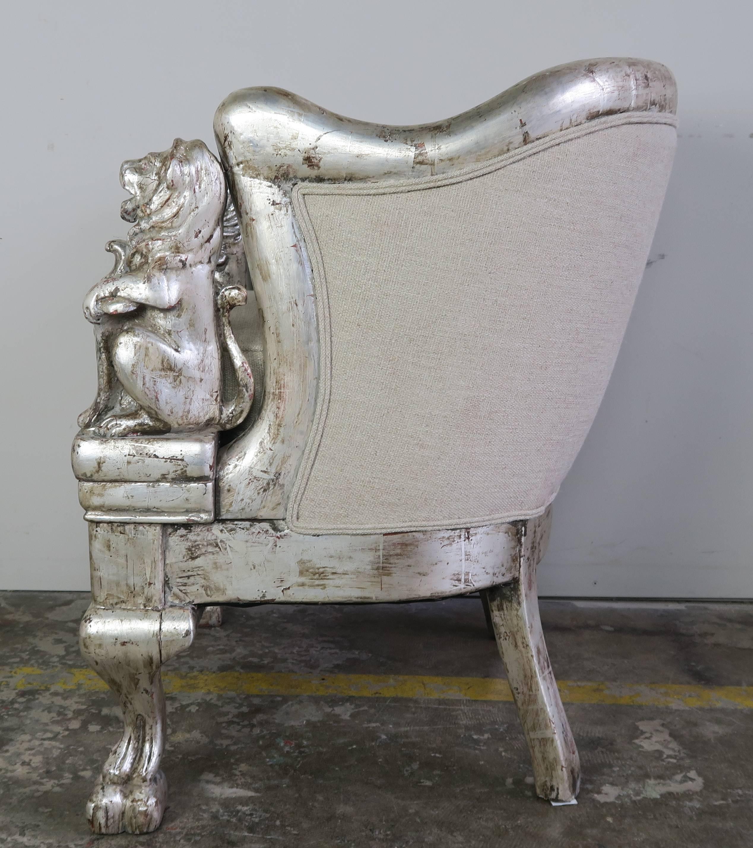 Pair of 19th century silvered armchairs with carved wood lions holding shields flanking both sides of each chairs. Beautiful carved lion feet in front. Newly upholstered in linen with loose seat cushion and double self cording.