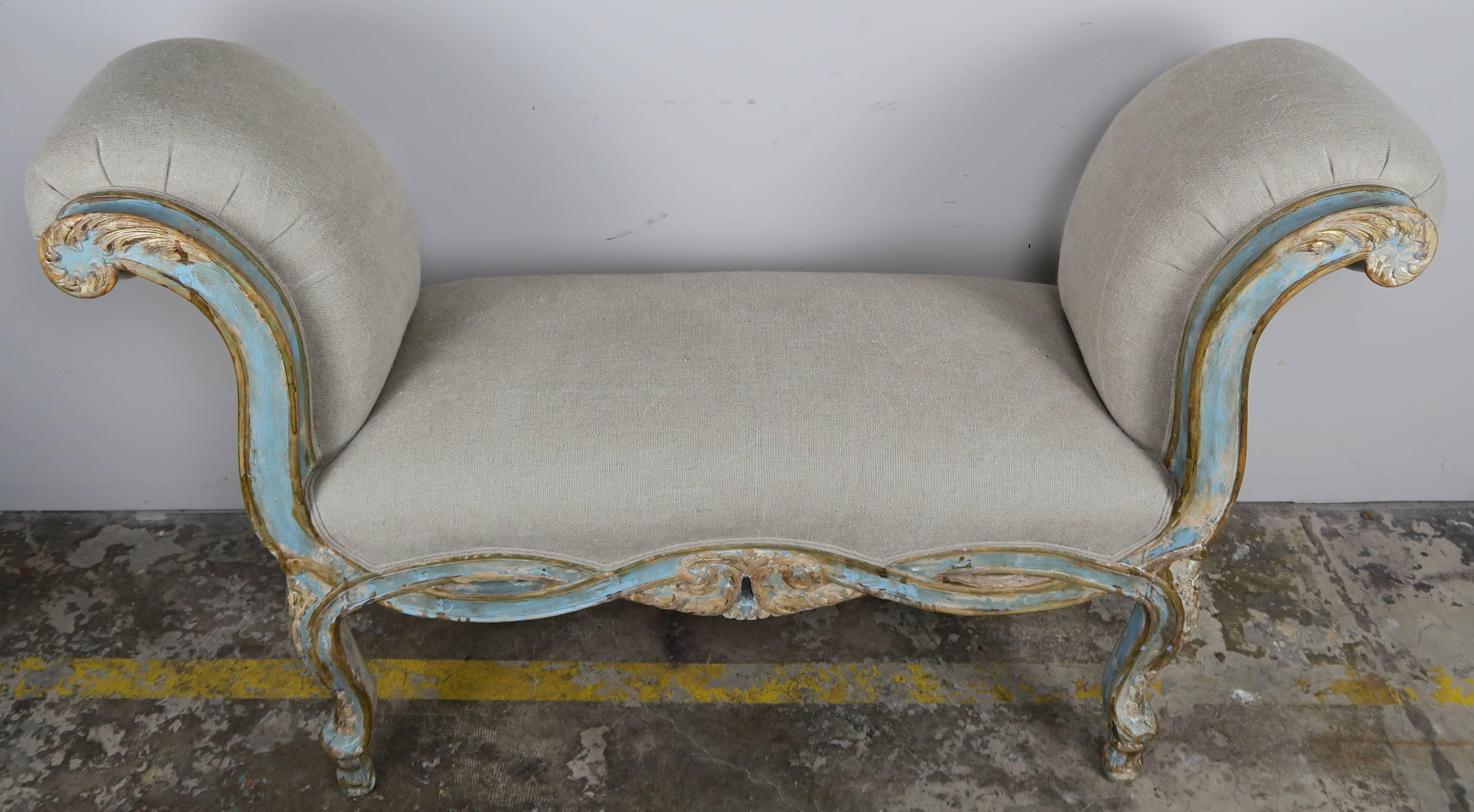 Pair of French Rococo style aqua and gold painted carved benches with rolled arms, cabriole legs, and braided apron. The benches are newly upholstered in a washed Belgium linen with double self cord detail.