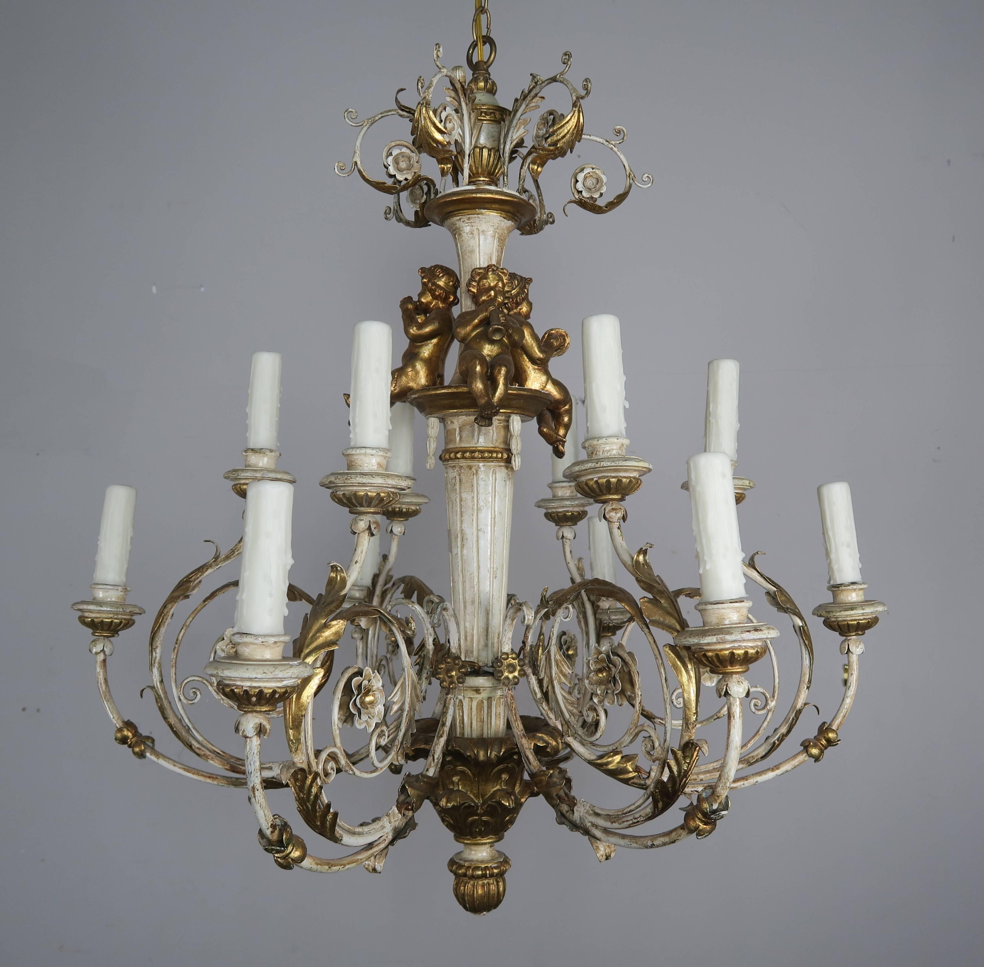 Italian twelve-light Rococo style chandelier with carved wood center column, cherubs playing instruments, bottom finial and wooden bobeches. Scrolled iron arms with acanthus leaf detail. The chandelier has been completely rewired with drip wax