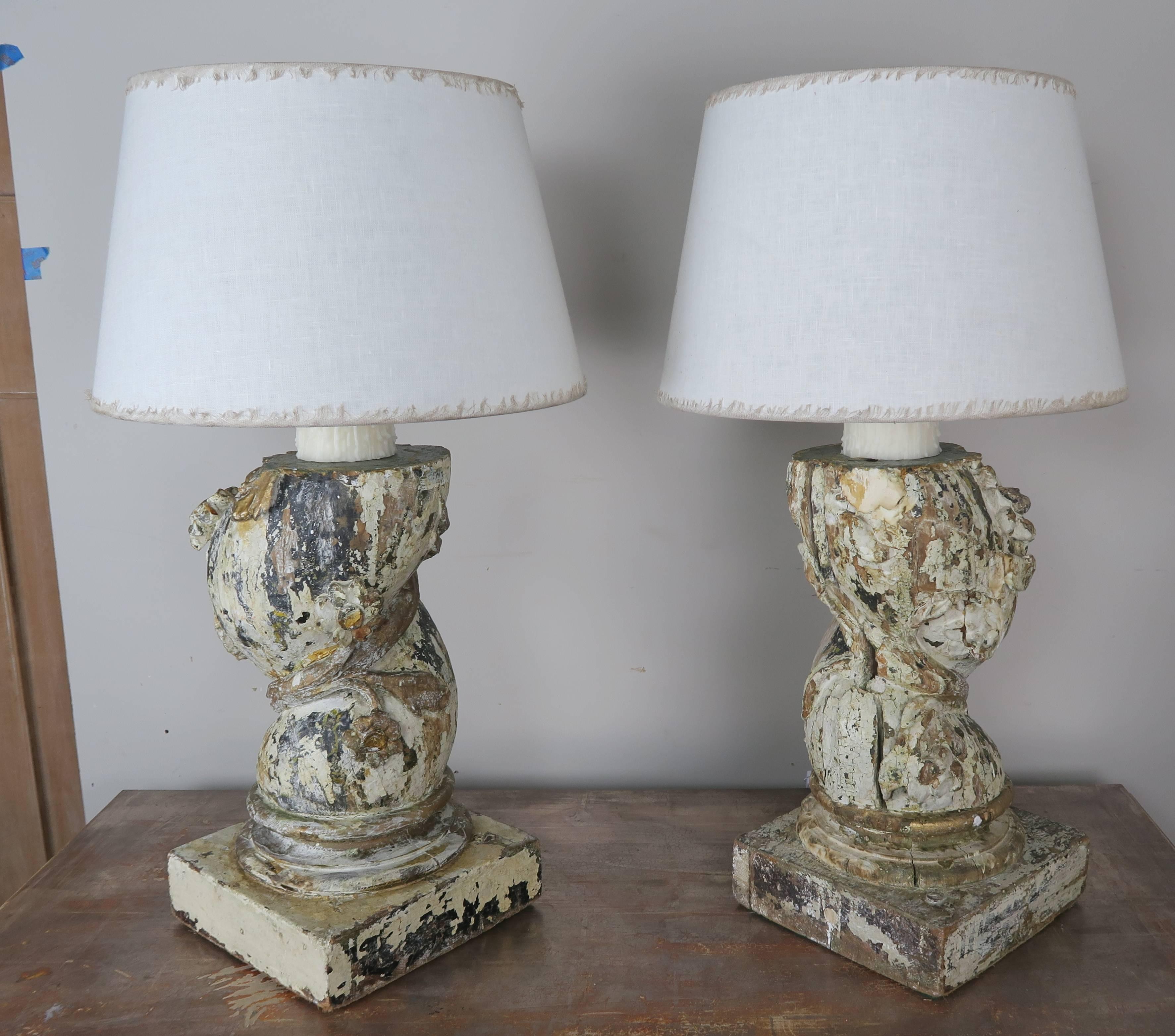 Pair of 19th century Italian carved painted capital fragments that have been mounted into lamps with drip wax candles. The lamps are crowned with white linen shades with eye lash fringe detail.
Shade size: 16