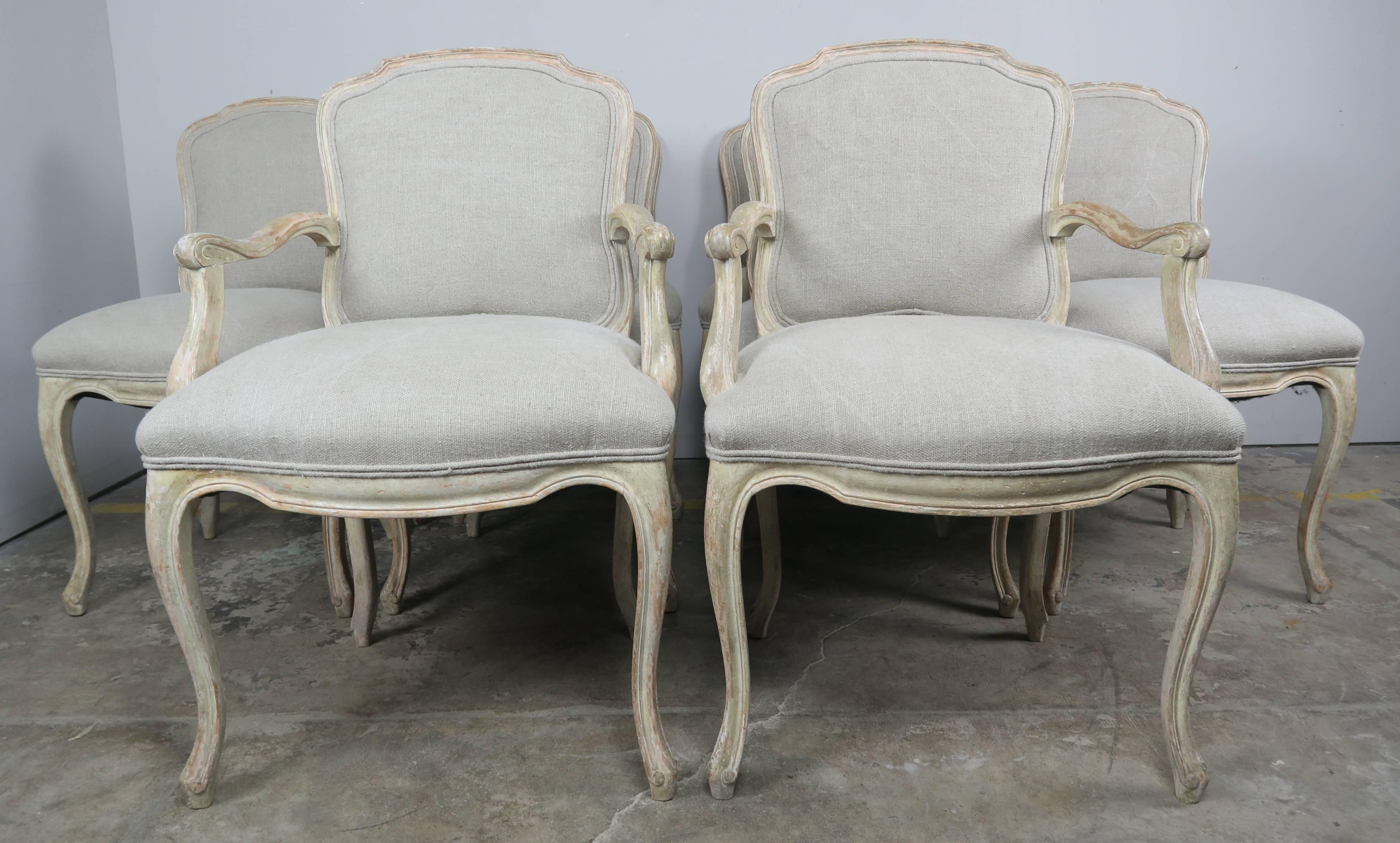 Set of ten French Louis XV style dining chairs with a beautiful worn painted finish. The vintage set of chairs have been newly upholstered in an oatmeal colored Belgium linen with self cord detail.

Measures: Armchair size: 25