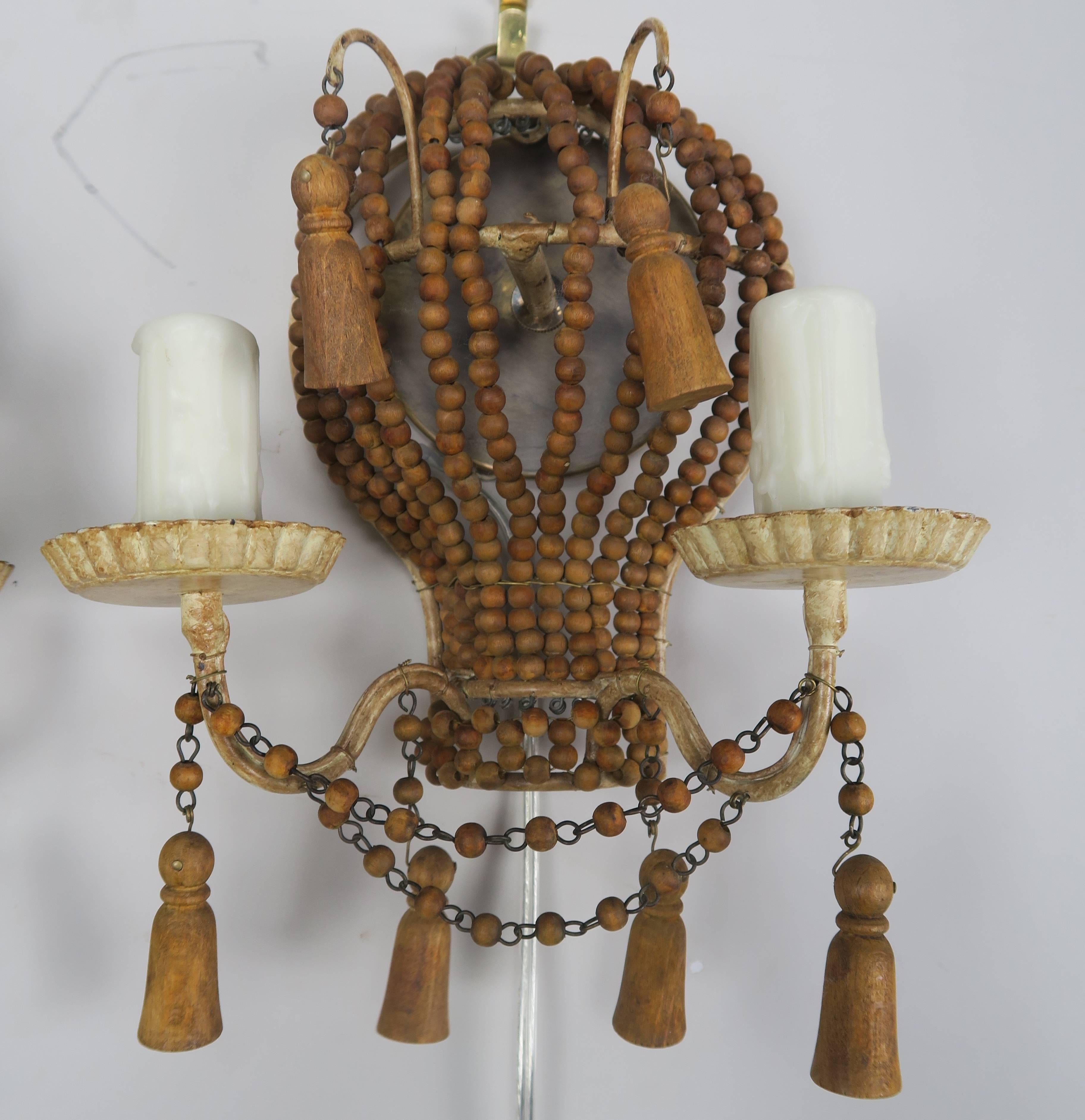 Pair of petite two-light wood beaded balloon sconces with wood tassels, circa 1920s. The sconces have been newly rewired with drip wax candle covers.